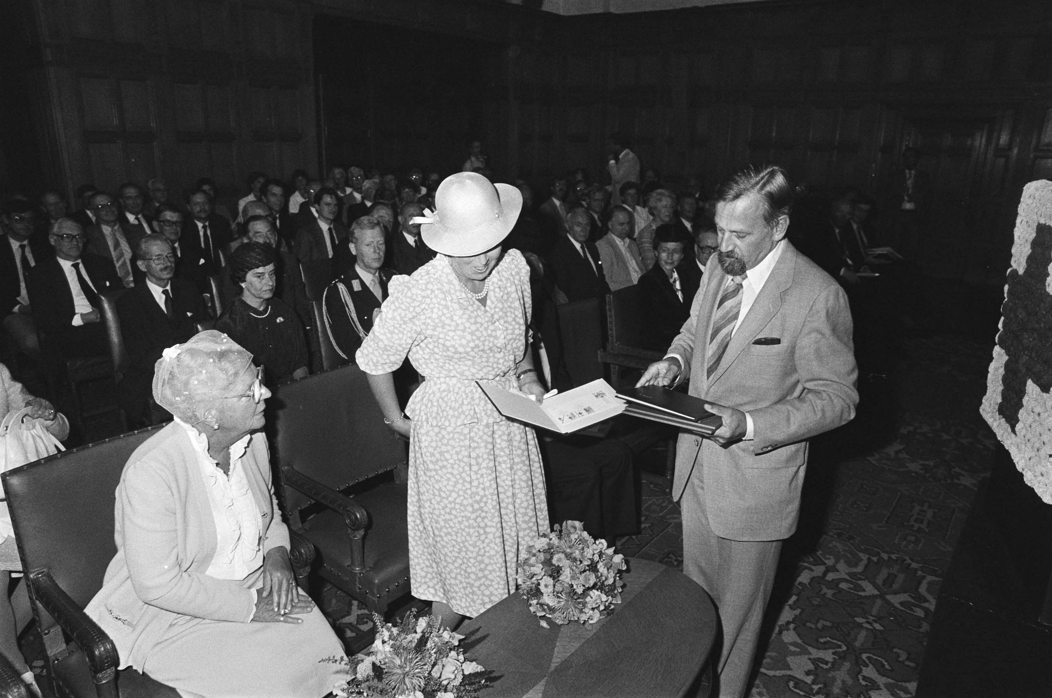 Koningin Beatrix en prinses Juliana bij de presentatie van de Rode Kruiszegels '83 in het Vredespaleis in Den Haag — Koningin Beatrix neemt de postzegels in ontvangst — Foto: Antonisse, Marcel / Anefo. Licentie: Set B: Rechtenvrij / Publiek Domein. Bron: Nationaal Archief. http://hdl.handle.net/10648/ad2cf848-d0b4-102d-bcf8-003048976d84