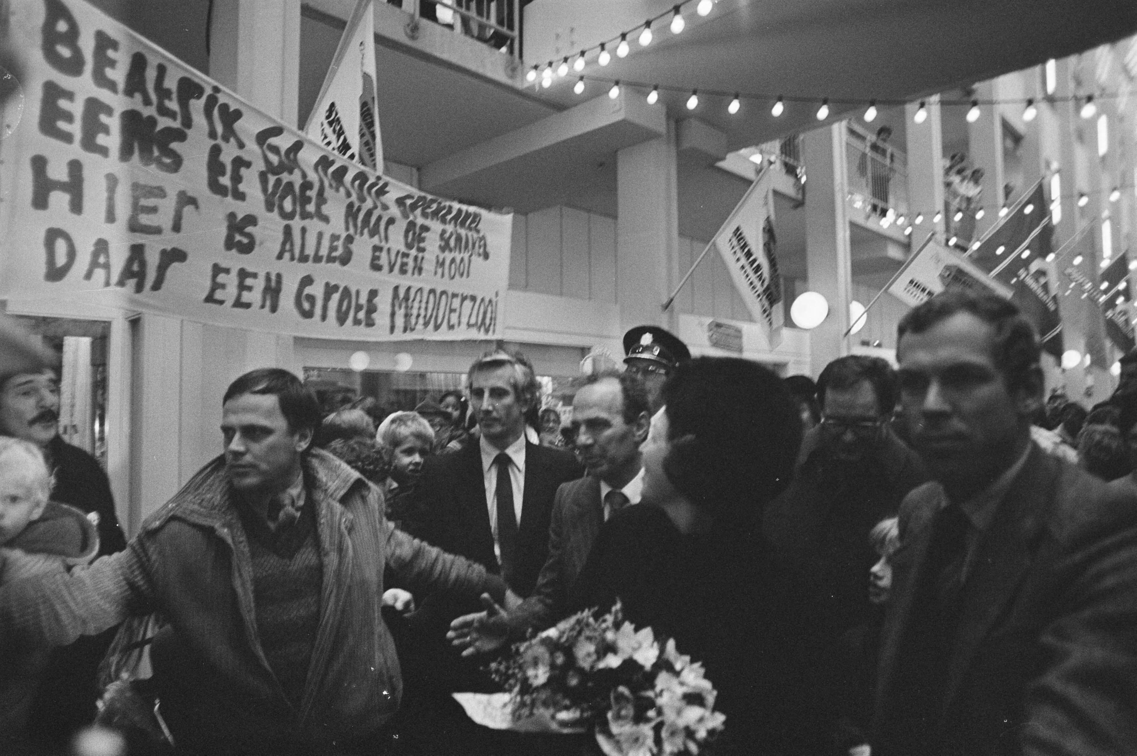 Koningin Beatrix bezoekt Almere in verband met het 5-jarig bestaan — In Almere Stad hingen spandoeken omdat de route van Beatrix schoon was en de rest modderig; rechts Han Lammers — Foto: Croes, Rob C. / Anefo. Licentie: Set B: Rechtenvrij / Publiek Domein. Bron: Nationaal Archief. http://hdl.handle.net/10648/ad09fcbc-d0b4-102d-bcf8-003048976d84