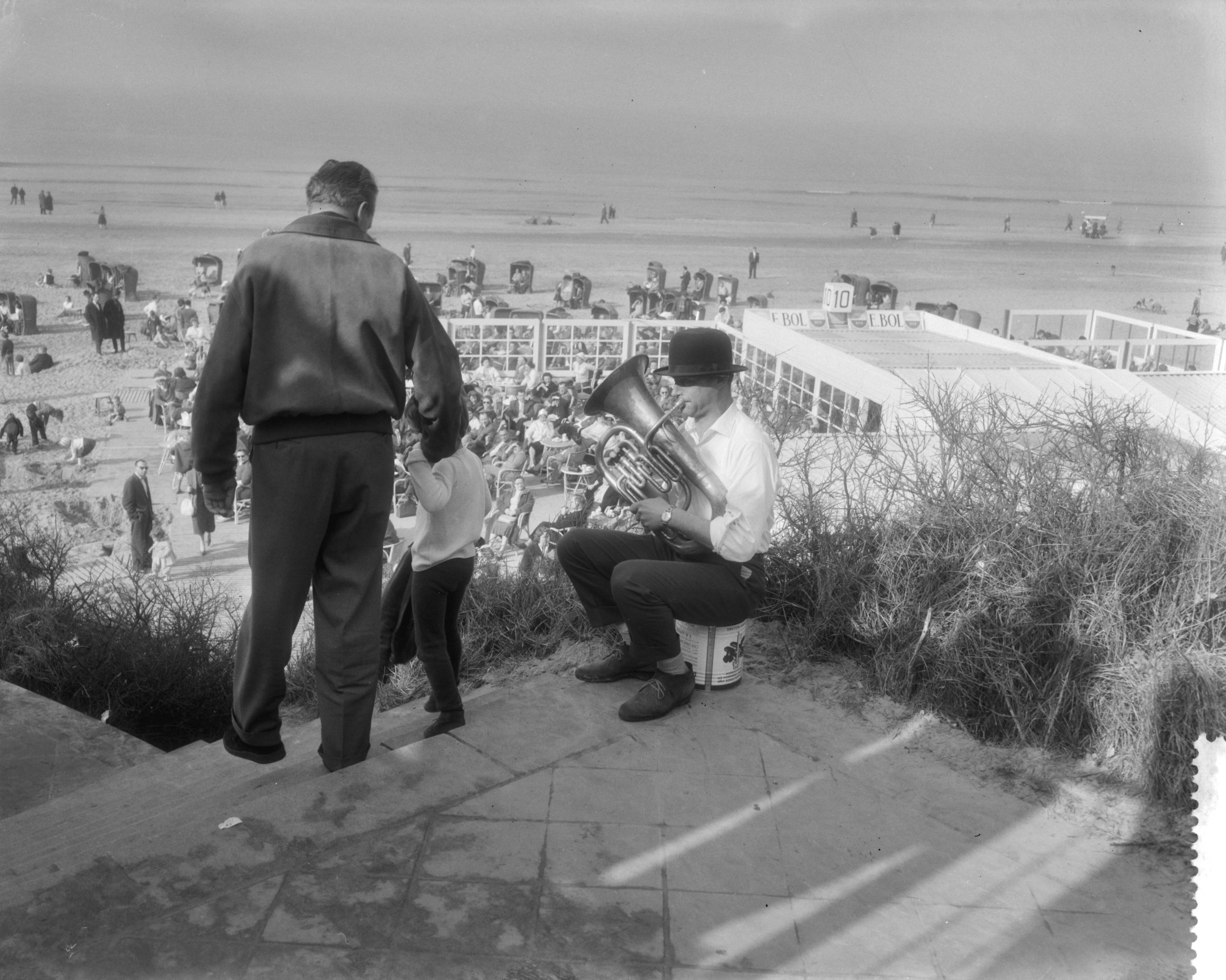Fotocollectie Anefo — Drukte aan het strand te Zandvoort i.v.m. het mooie weer. Muzikant met tuba en bolhoed — Foto: Pot, Harry / Anefo. Licentie: Set B: Rechtenvrij / Publiek Domein. Bron: Nationaal Archief. http://hdl.handle.net/10648/a98eaed4-d0b4-102d-bcf8-003048976d84