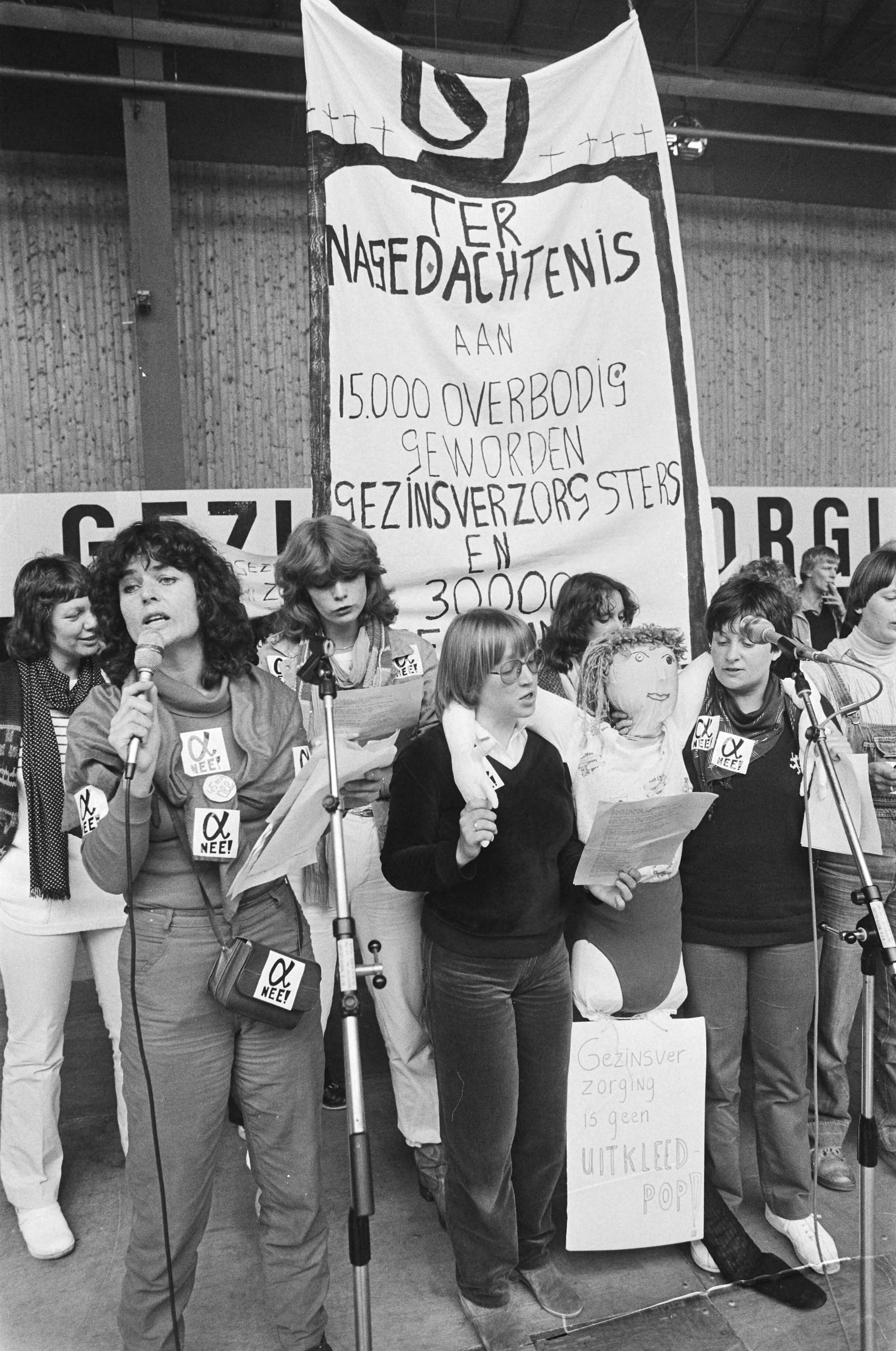 Fotocollectie Anefo — Manifestatie in Den Haag tegen bezuiniging in de gezinsverzorging in Houtrusthallen. Aktievoerders op het toneel met "uitgeklede pop" — Foto: Dijk, Hans van / Anefo. Licentie: Set B: Rechtenvrij / Publiek Domein. Bron: Nationaal Archief. http://hdl.handle.net/10648/ad15fc42-d0b4-102d-bcf8-003048976d84