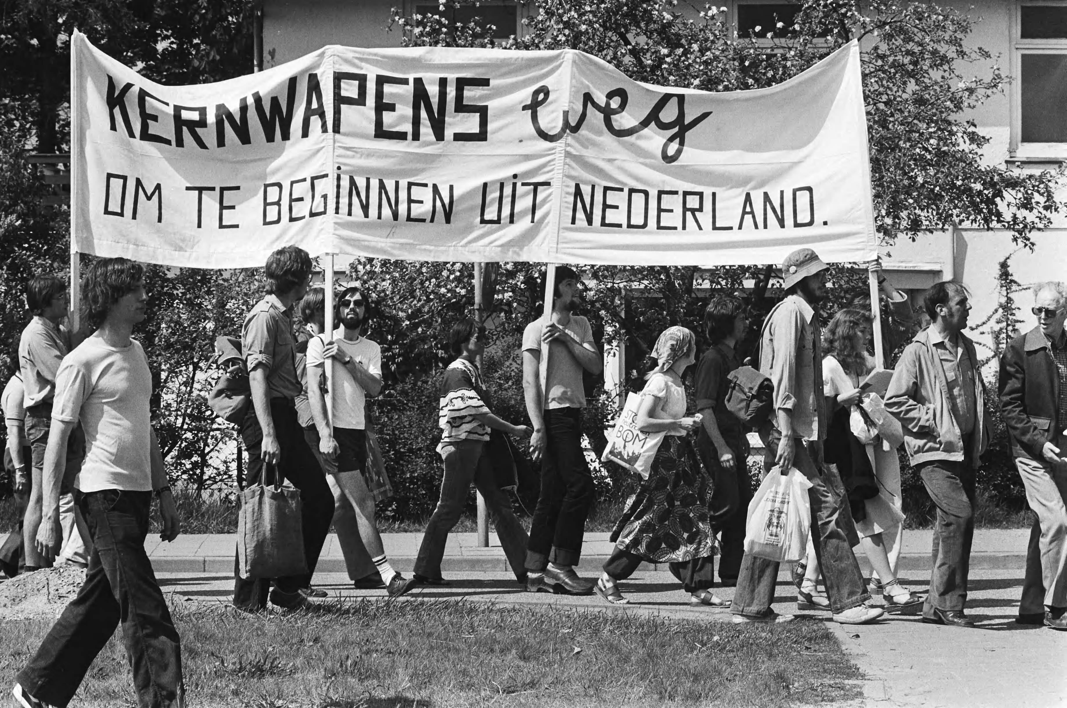 Demonstratie in Soesterberg tegen kernbewapening en opslag van kernwapens op vliegveld Soesterberg — Op de spandoeken staat o.a. "Kernwapens weg - om te beginnen uit Nederland" — Foto: Croes, Rob C. / Anefo. Licentie: Set B: Rechtenvrij / Publiek Domein. Bron: Nationaal Archief. http://hdl.handle.net/10648/acca71f0-d0b4-102d-bcf8-003048976d84