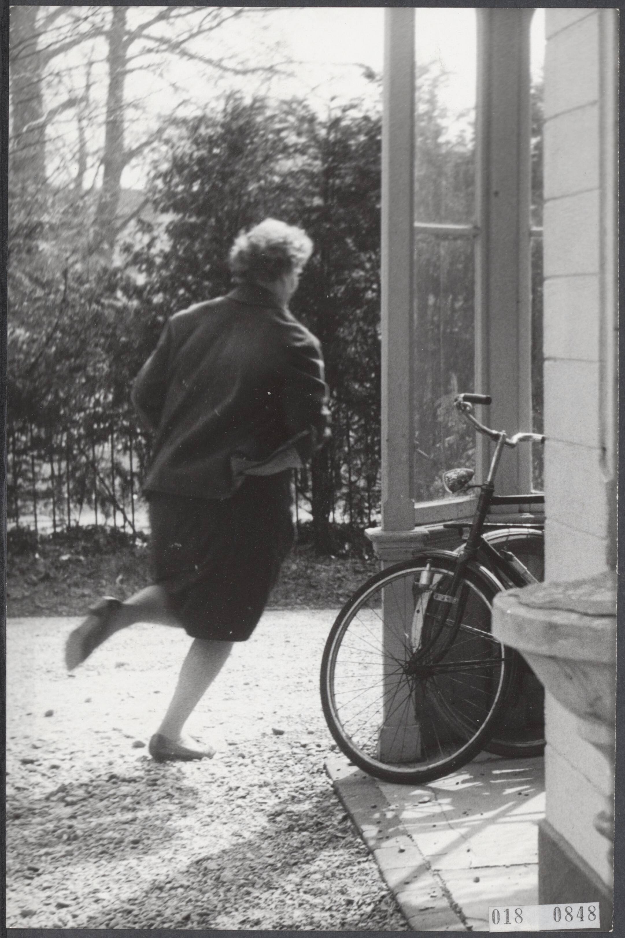 Fotocollectie Elsevier Binnenland — Carlisten in Hilversums pension. De pas in het nieuws gekomen villa aan de Boomberglaan no. 21 in Hilversum is de laatste dagen het doelwit geweest van vele fotografen., hierdoor is eigenaresse mevr. Pronk erg schuw geworden voor alles wat met kranten te maken heeft. Op deze foto "vlucht" mevr. Pronk vrijdagmiddag voor de camera om enkele seconden na een belsignaal te openen en te vragen wat er aan de hand was — Foto: Gelderen, Hugo van / Anefo. Licentie: Set B: Rechtenvrij / Publiek Domein. Bron: Nationaal Archief. http://hdl.handle.net/10648/adc3851a-d0b4-102d-bcf8-003048976d84