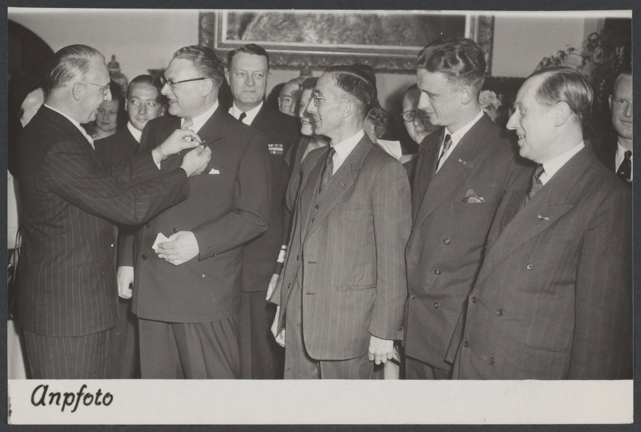 Illegaliteit — In tegenwoordigheid van Clarence E. Hunter, chef van de E.C.A. missie; admiraal E. Forrestal; Capt. Basil N. Rittenhouse, commander E.K. Solenberger; vice-admiraal T. Stephens, luitenant-kolonel R. Beers, mevr. Heaerling en tal van andere Amerikaanse en Nederlandse autoriteiten werd op het buitengoed "Vluemert" te Wassenaar namens de minister van Oorlog het mobilisatie-oorlogskruis uitgereikt aan de heren : R.P. Schoonheim (importeur van steenkool), J.A.J. Houtzager (accountant), S.A. van der Beek (afd. Internationaal Vervoer der Eigenvervoers Organisatie) en de arts G.I. Dommers (werkzaam bij de Volharding), allen uit Den Haag. De onderscheiding werd toegekend vanwege hun daden van persoonlijke moed en opofferingsgezindheid bij de strijd tegen de Duitsers. A.C. van Montfoort (geheel links) speldt de onderscheiding op. Van rechts naar links de heren Dommers, van den Beek, Houtzager en Schoonheim — Foto: ANP / RVD of rechtenvrij. Licentie: Set B: Rechtenvrij / Publiek Dom