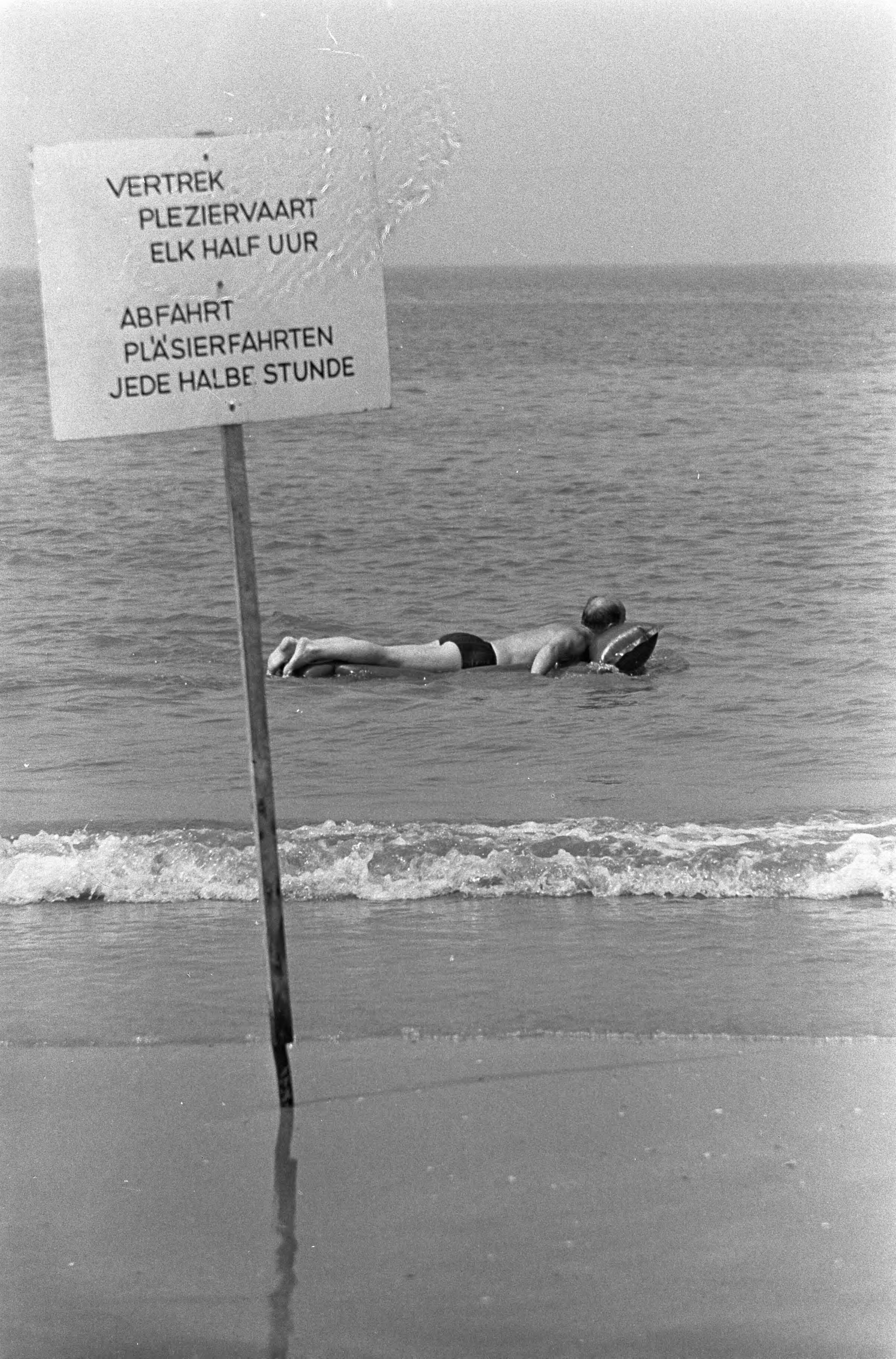 Fotocollectie Anefo — Zandvoort warmte, man op luchtbed in zee (met bordje pleziervaart) — Foto: Nijs, Jac. de / Anefo. Licentie: Set B: Rechtenvrij / Publiek Domein. Bron: Nationaal Archief. http://hdl.handle.net/10648/aaedfdca-d0b4-102d-bcf8-003048976d84