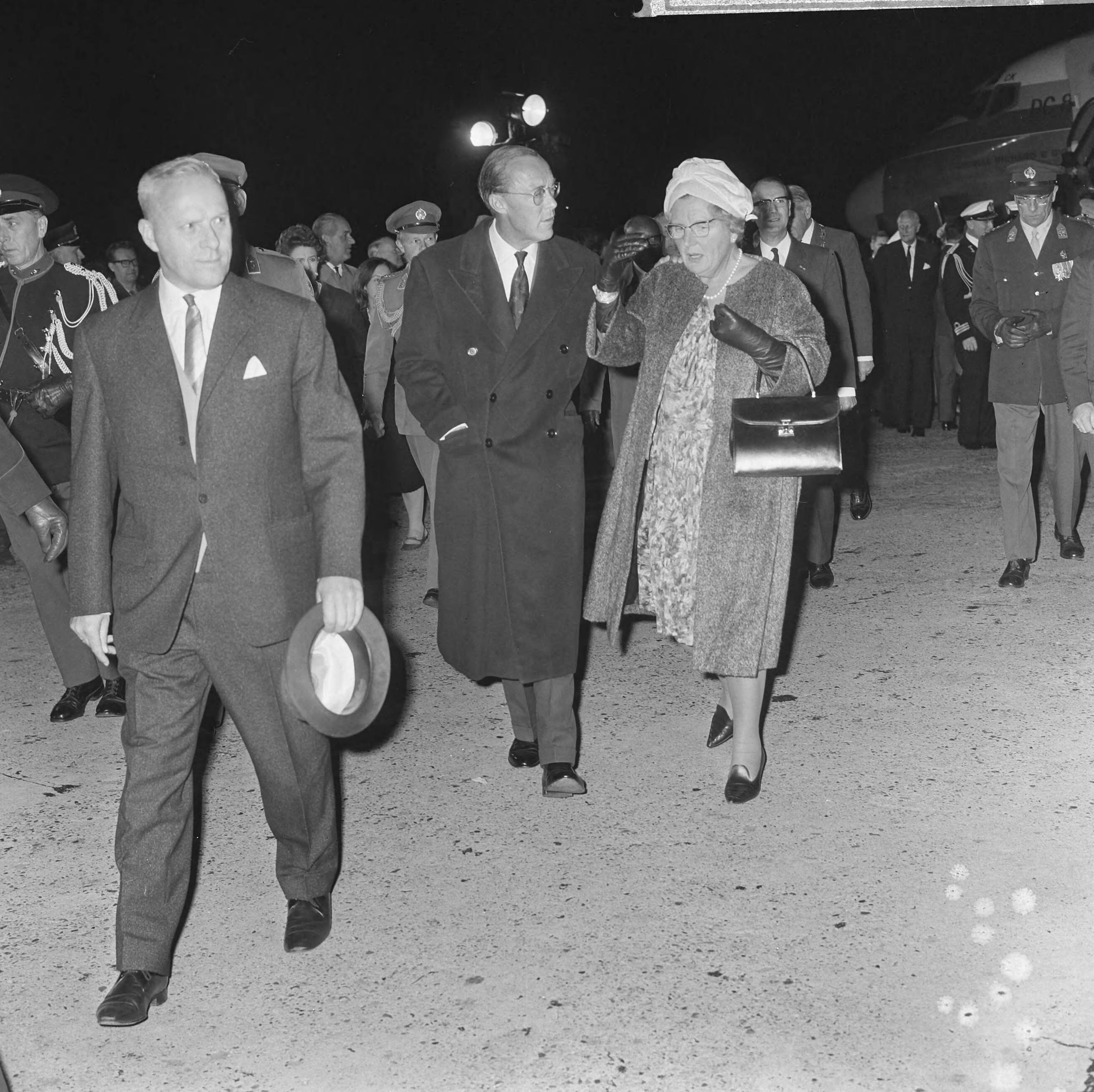 Aankomst van koningin Juliana en prins Bernhard op Schiphol na een bezoek aan de Antillen en Suriname — Koningn Juliana in gezelschap van haar echtgenoot prins Bernhard — Foto: Koch, Eric / Anefo. Licentie: Set B: Rechtenvrij / Publiek Domein. Bron: Nationaal Archief. http://hdl.handle.net/10648/aac7107a-d0b4-102d-bcf8-003048976d84