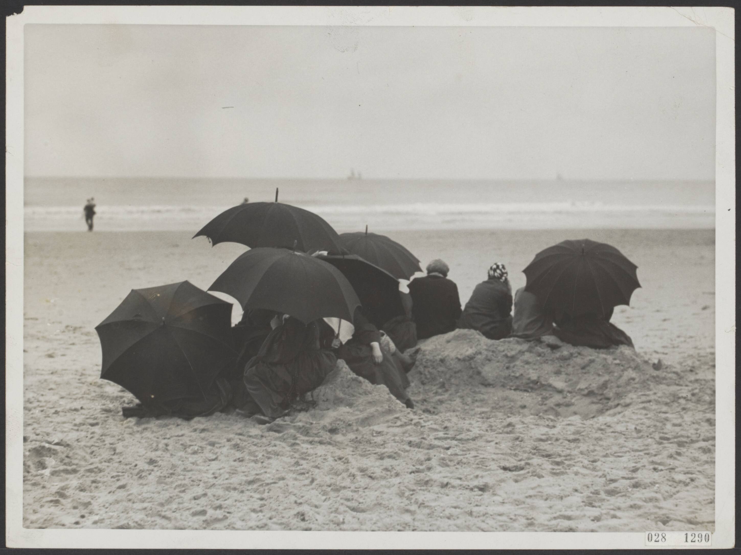 Fotocollectie Elsevier Binnenland — Dagjesmensen trotseren de regen aan het strand van Scheveningen — Foto: N.V. Polygoon. Licentie: Set B: Rechtenvrij / Publiek Domein. Bron: Nationaal Archief. http://hdl.handle.net/10648/ade051fe-d0b4-102d-bcf8-003048976d84