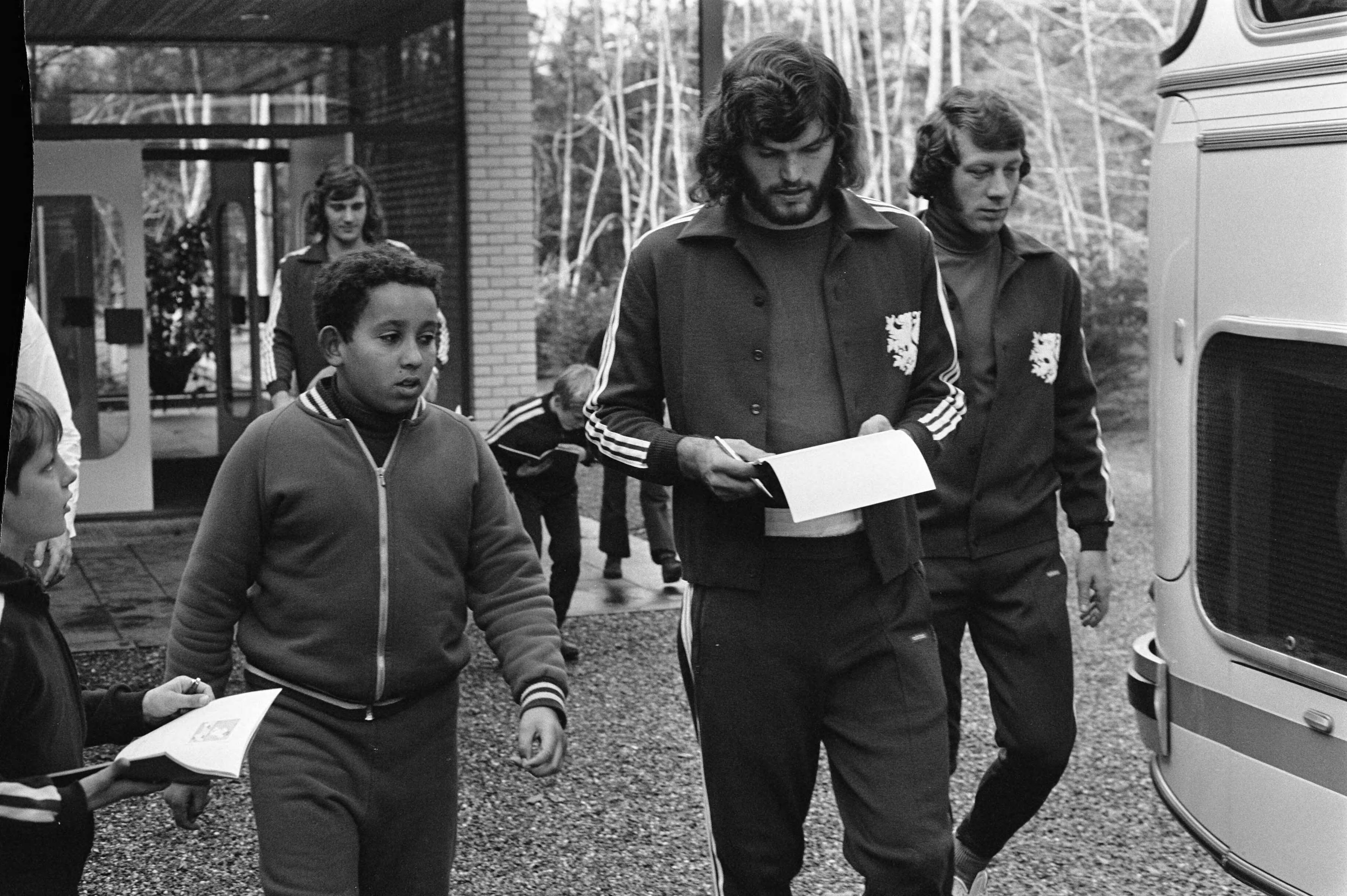 Fotocollectie Anefo — Training selectie Nederlands elftal in Zeist voor wedstrijd tegen Belgie, nummer 18 en 19 Hulshoff geeft handtekening — Foto: Mieremet, Rob / Anefo. Licentie: Set B: Rechtenvrij / Publiek Domein. Bron: Nationaal Archief. http://hdl.handle.net/10648/abfd5c88-d0b4-102d-bcf8-003048976d84