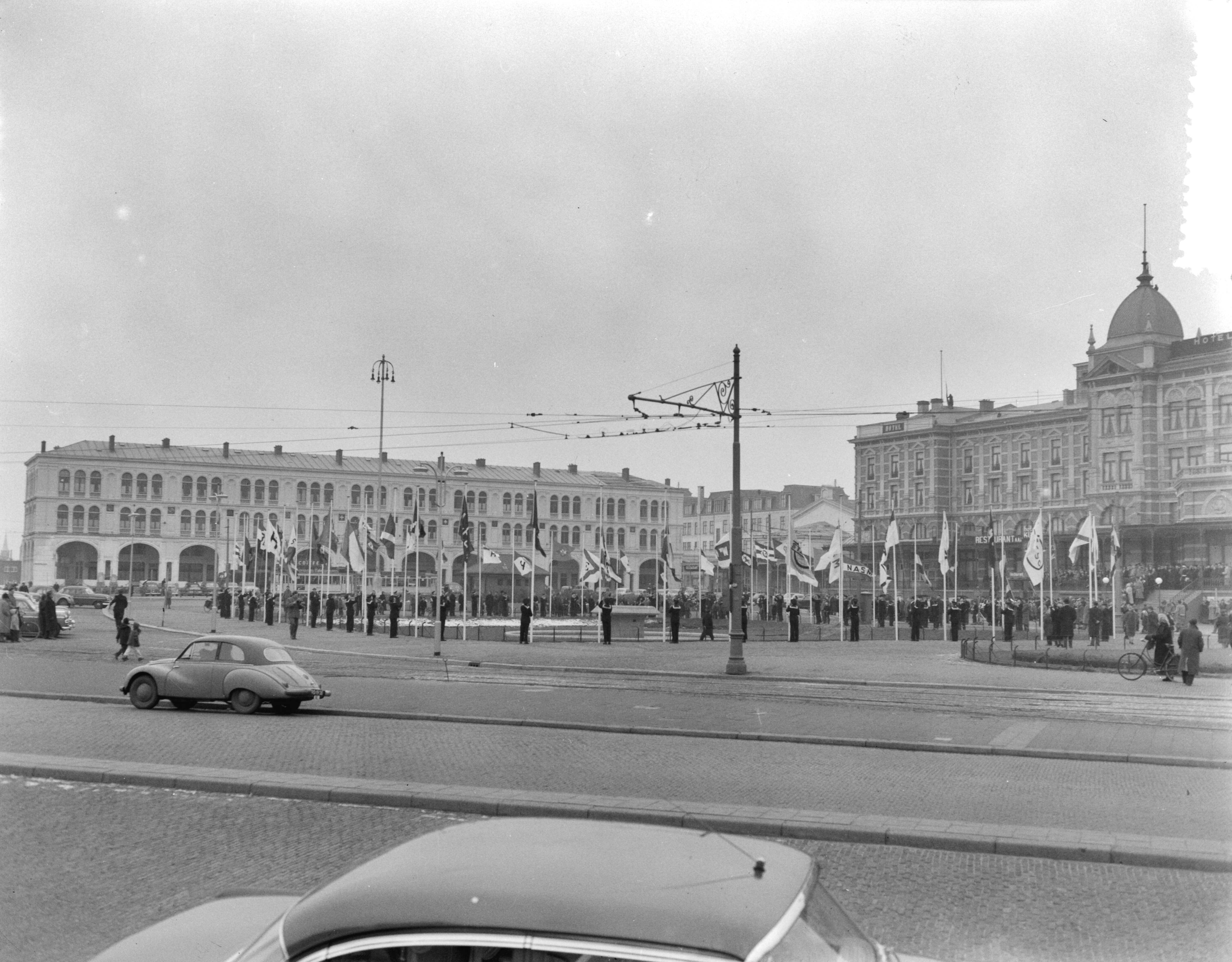 Fotocollectie Anefo — Viering gouden jubileum (50-jarig bestaan) van de Nederlandsche Reedersvereniging in het Kurhaus te Scheveningen. Op het Gevert Deynootplein worden vlaggen van rederijen gehesen door jongens van de "Pollux" uit Amsterdam — Foto: Pot, Harry / Anefo. Licentie: Set B: Rechtenvrij / Publiek Domein. Bron: Nationaal Archief. http://hdl.handle.net/10648/a931331c-d0b4-102d-bcf8-003048976d84