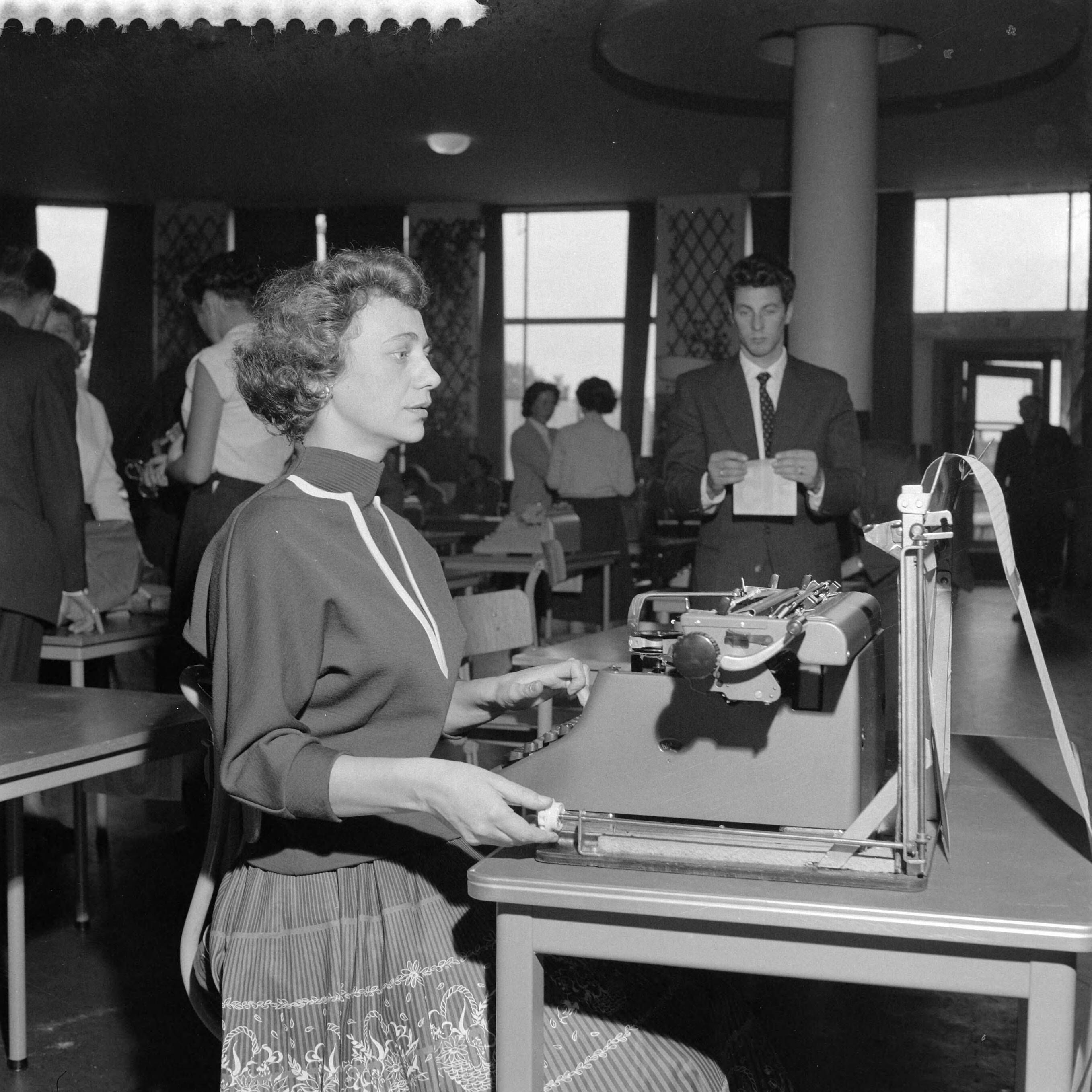 Fotocollectie Anefo — Kampioenschap machineschrijven in de Houtrusthal in Den Haag — Foto: Behrens, Herbert F. / Anefo. Licentie: Set B: Rechtenvrij / Publiek Domein. Bron: Nationaal Archief. http://hdl.handle.net/10648/a96b2838-d0b4-102d-bcf8-003048976d84