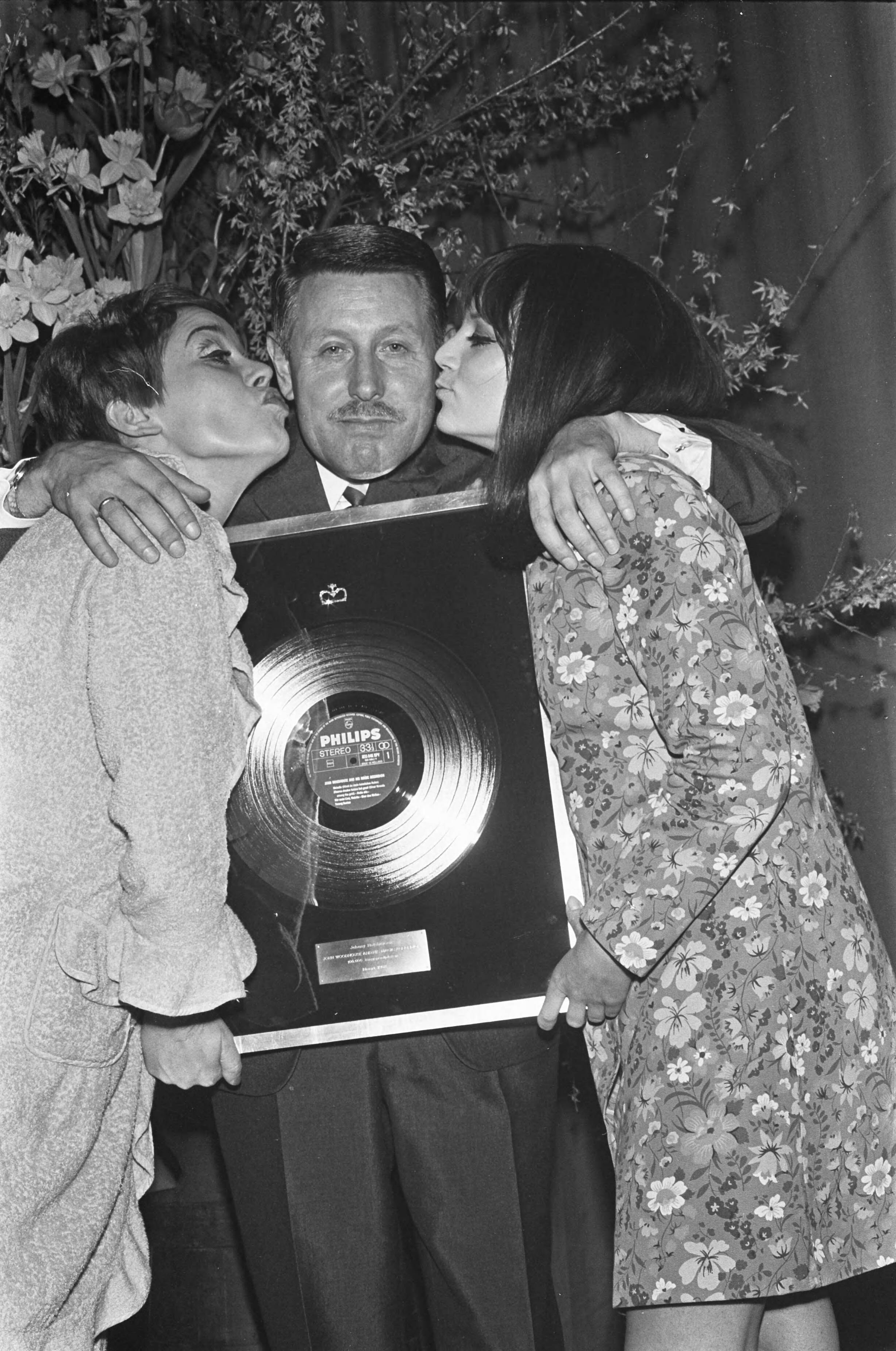 Fotocollectie Anefo — Platina plaat voor accordeonist John Woodhouse (Johan Hendrik Holshuysen) ; John gefeliciteerd door links Connie Vandenbos (Jacoba Adriana Hollestelle) en Thérèse Steinmetz te Laren — Foto: Kroon, Ron / Anefo. Licentie: Set B: Rechtenvrij / Publiek Domein. Bron: Nationaal Archief. http://hdl.handle.net/10648/ab39ee88-d0b4-102d-bcf8-003048976d84