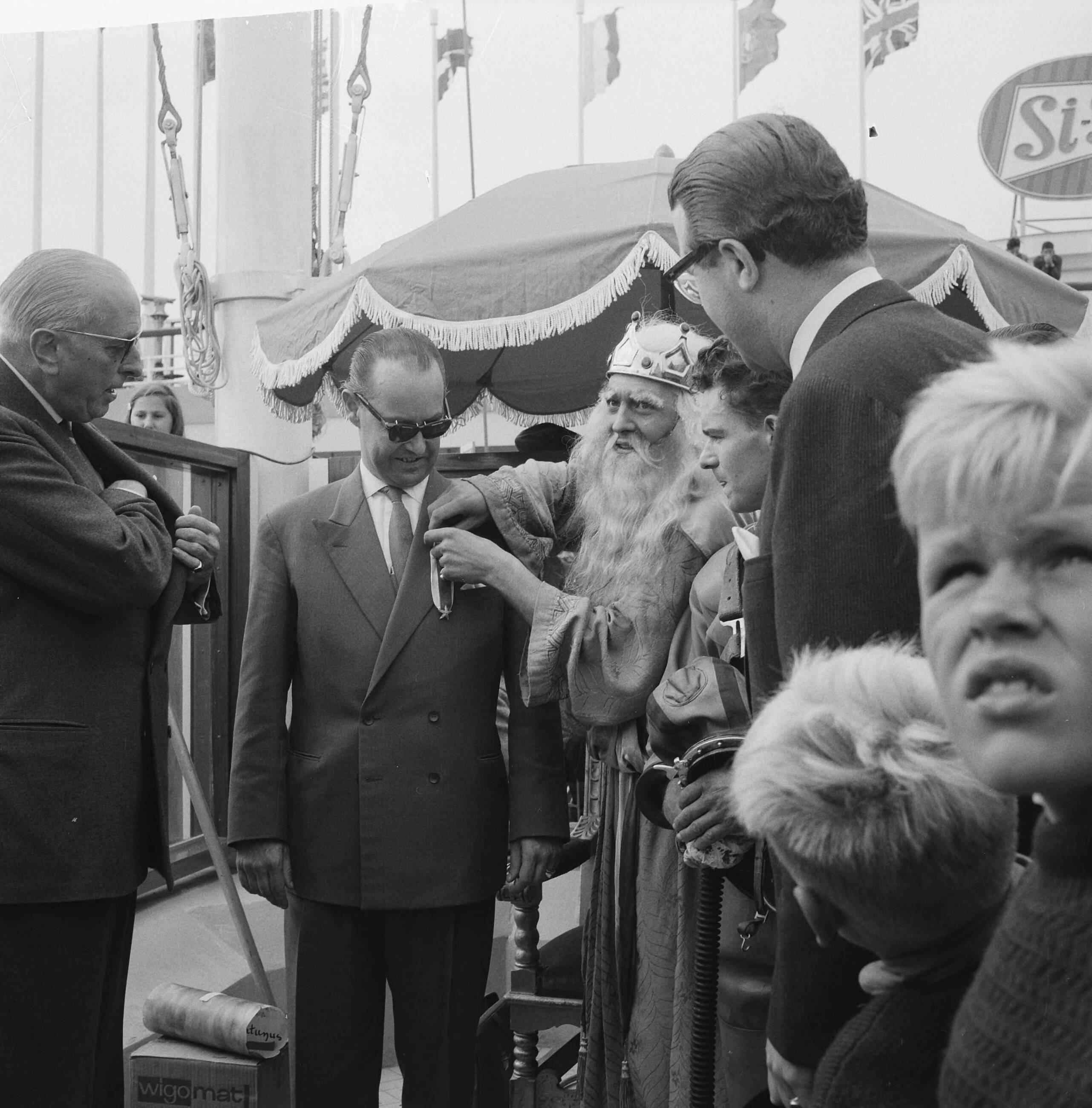 Fotocollectie Anefo — Miljoenste bezoeker op Scheveningse Pier. Neptunus speldt de 39-jarige Rotterdamse zakenman R. Driebeek de versierelen behorend bij het ridderschap in de Orde van de Zilveren Zeester op — Foto: Lindeboom, Henk / Anefo. Licentie: Set B: Rechtenvrij / Publiek Domein. Bron: Nationaal Archief. http://hdl.handle.net/10648/a9dd2aaa-d0b4-102d-bcf8-003048976d84