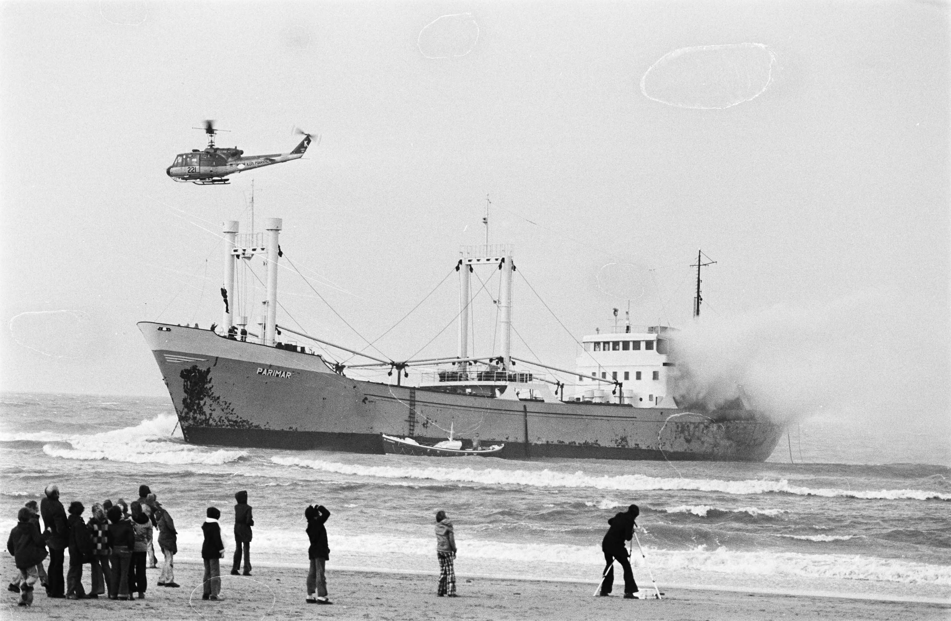 Fotocollectie Anefo — Griekse kustvaarder Parimar in brand op strand bij Scheveningen; brandweerman wordt vanuit helicopter op schip neer gelaten, publiek kijkt vanaf het strand toe — Foto: Verhoeff, Bert / Anefo. Licentie: Set B: Rechtenvrij / Publiek Domein. Bron: Nationaal Archief. http://hdl.handle.net/10648/ac5d8e3c-d0b4-102d-bcf8-003048976d84
