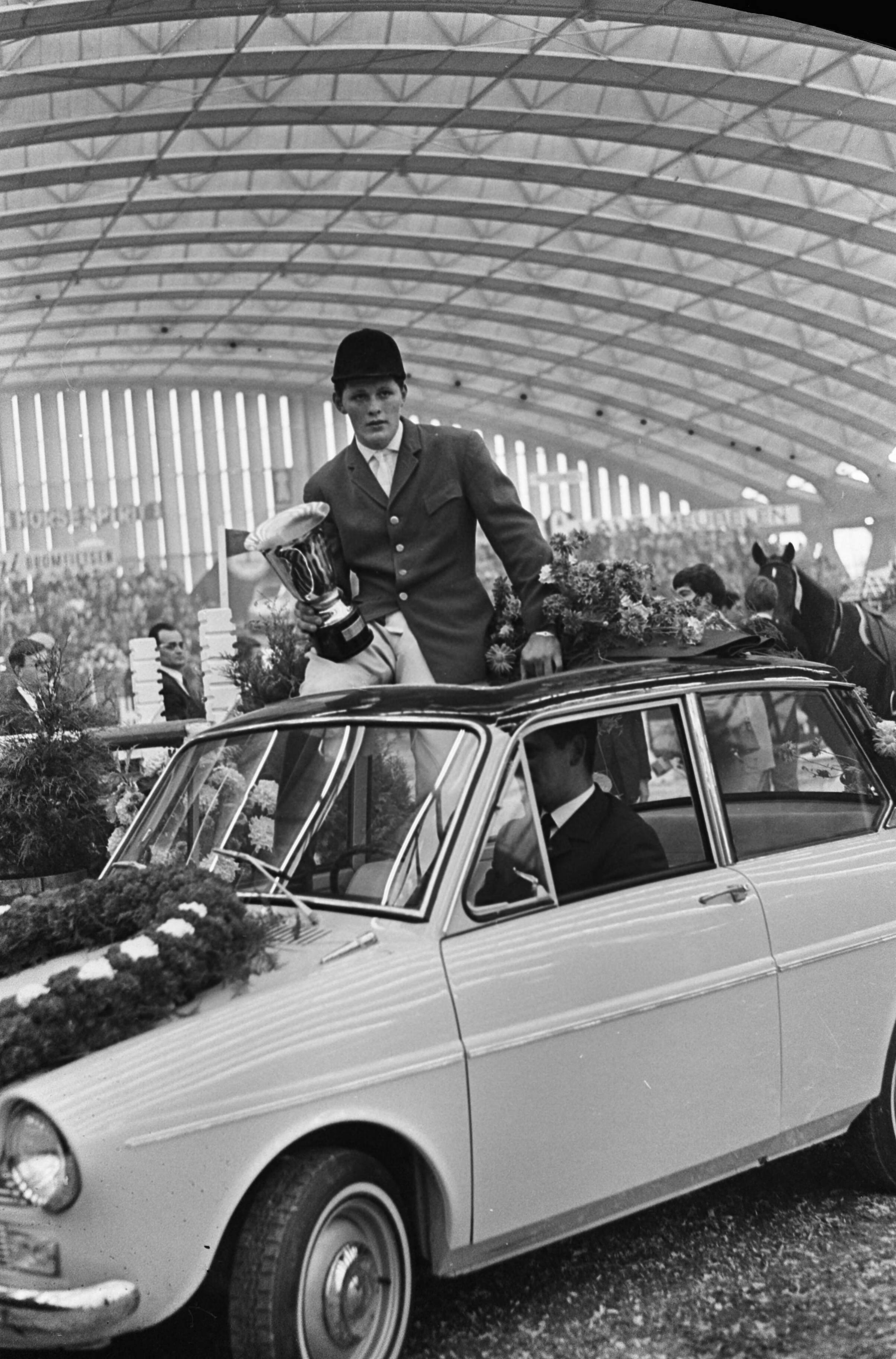 Jumping Amsterdam 1965 in de RAI te Amsterdam — De Duitse springruiter Gerd Wiltfang, winnaar van de Grote Prijs van Amsterdam, poseert op de auto (een DAF) die hij als extra-prijs kreeg — Foto: Fotograaf Onbekend / Anefo. Licentie: Set B: Rechtenvrij / Publiek Domein. Bron: Nationaal Archief. http://hdl.handle.net/10648/aac8cb2c-d0b4-102d-bcf8-003048976d84