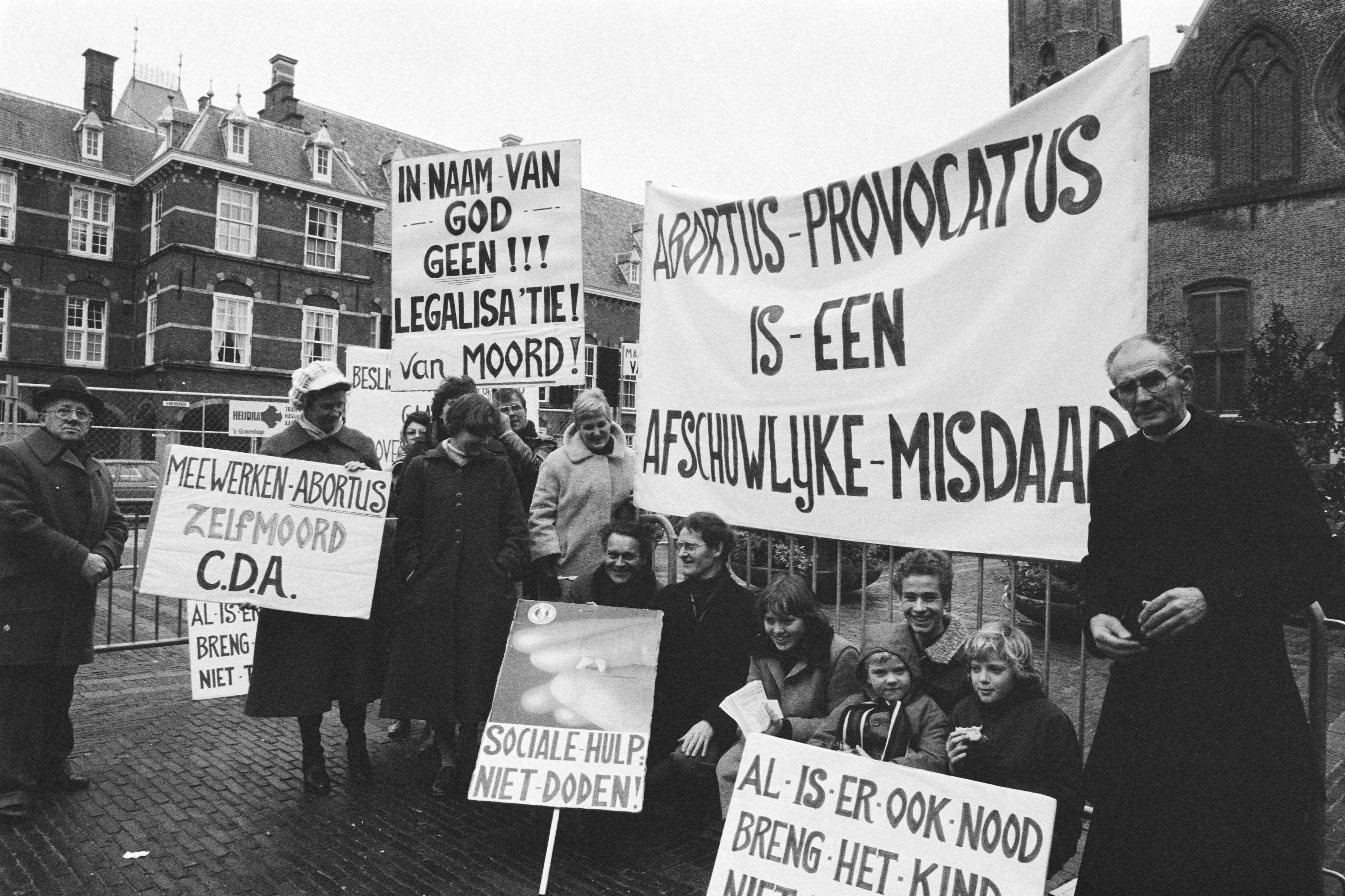 Fotocollectie Anefo — Demonstratie van tegenstanders van abortus op Binnenhof, Den Haag , demonstranten met in midden Pater Koopman — Foto: Dijk, Hans van / Anefo. Licentie: Set B: Rechtenvrij / Publiek Domein. Bron: Nationaal Archief. http://hdl.handle.net/10648/aced9658-d0b4-102d-bcf8-003048976d84