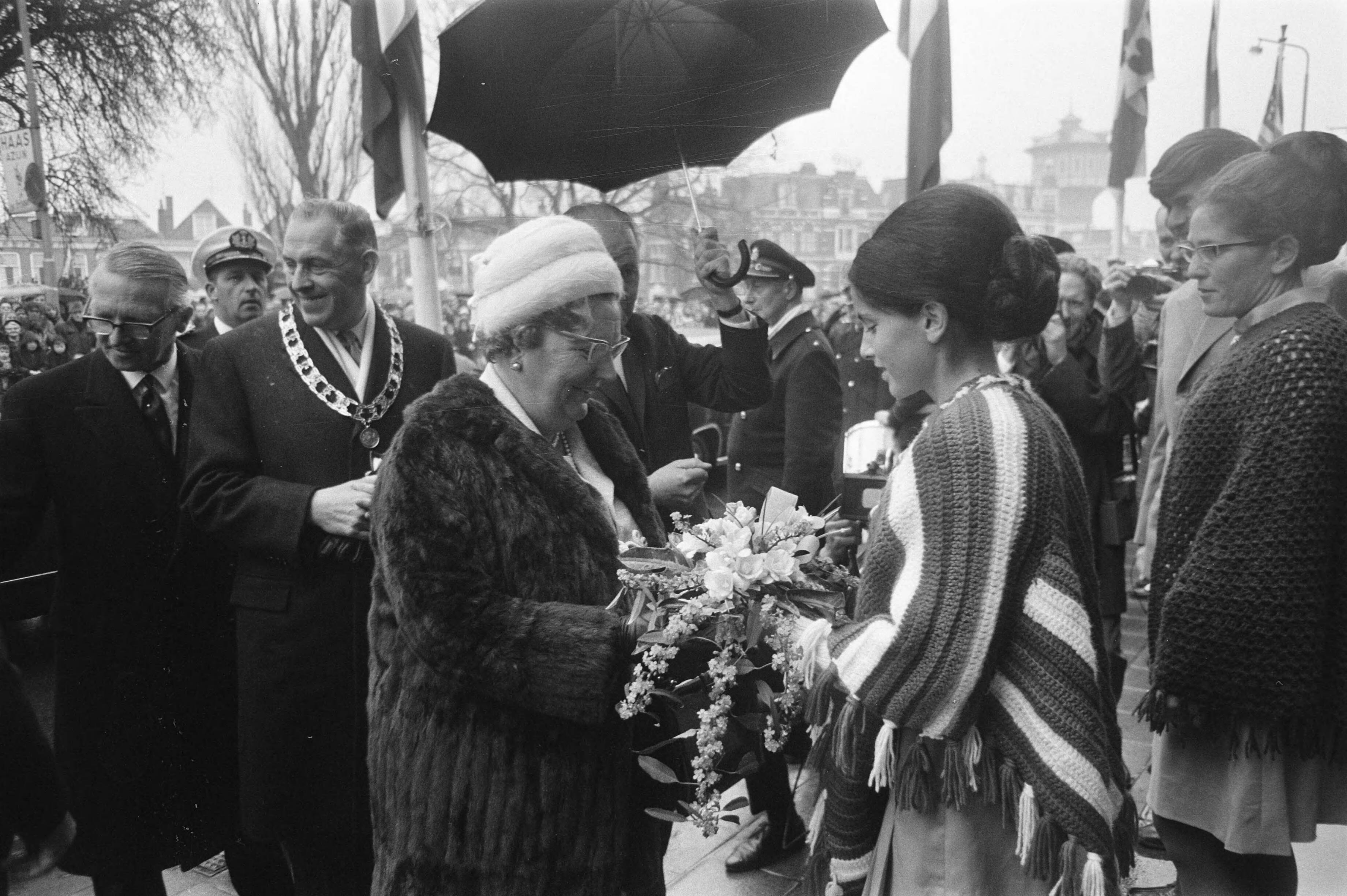 Herdenking in Leeuwarden van 25 jaar bevrijding van Friesland in aanwezigheid van koningin Juliana — Koningin Juliana krijgt bloemen aangeboden. Links burgemeester van Leeuwarden Brandsma — Foto: Fotograaf Onbekend / Anefo. Licentie: Set B: Rechtenvrij / Publiek Domein. Bron: Nationaal Archief. http://hdl.handle.net/10648/ab943eba-d0b4-102d-bcf8-003048976d84