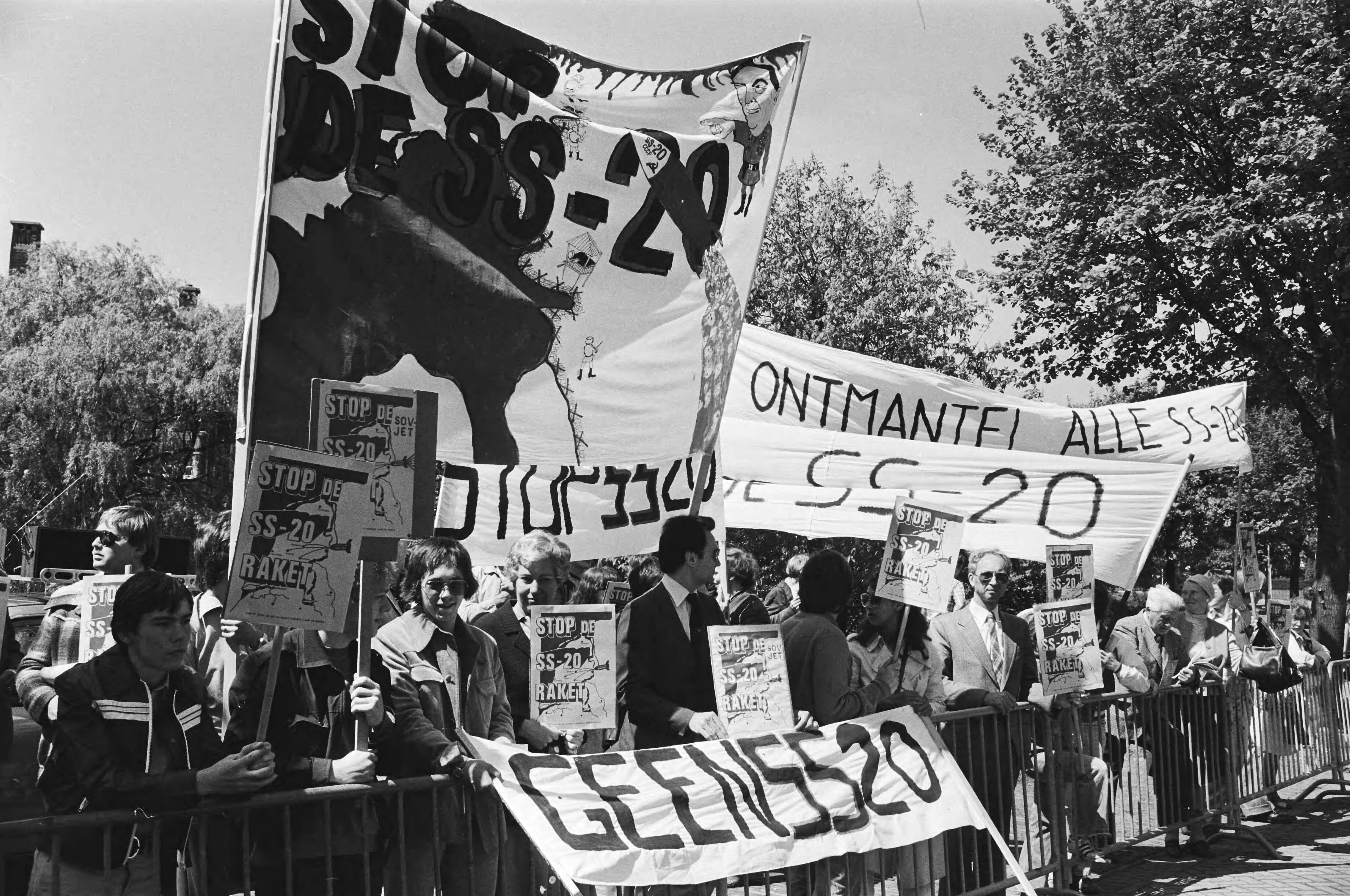 Demonstratie voor de Russische Ambassade in Den Haag tegen de fabrikage van de SS 20 raket — Demonstratie met spandoeken waarop o.a. de tekst "Ontmantel alle SS-20" en "Geen SS-20" — Foto: Suyk, Koen / Anefo. Licentie: Set B: Rechtenvrij / Publiek Domein. Bron: Nationaal Archief. http://hdl.handle.net/10648/acca6cc8-d0b4-102d-bcf8-003048976d84