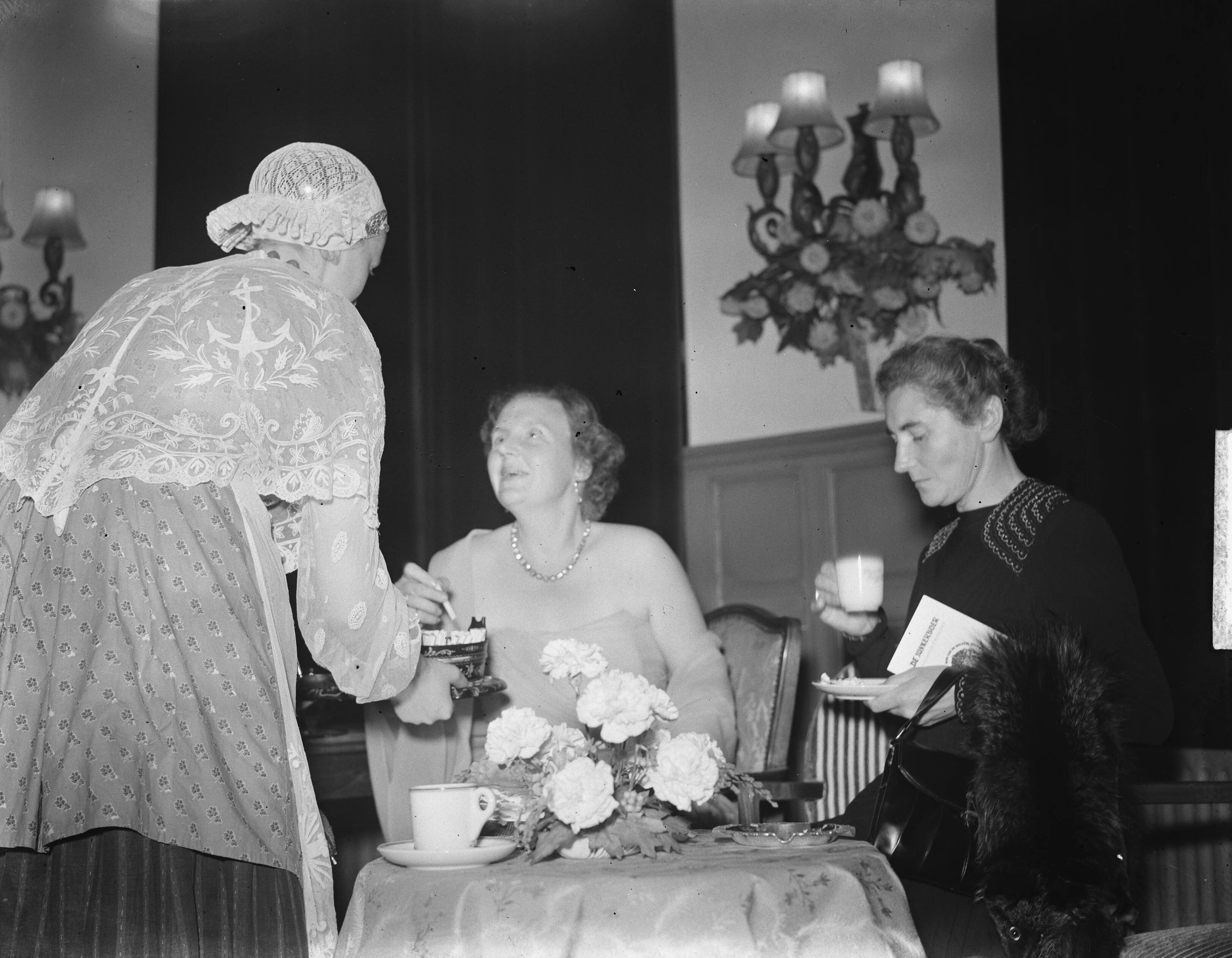 Koninklijk bezoek aan Friesland (1950) — Bezoek koningin Juliana en prins Bernhard aan Friesland. Leeuwarden. Galabijeenkomst. Koningin Juliana krijgt sigaretten aangeboden — Foto: Noske, J.D. / Anefo. Licentie: Set B: Rechtenvrij / Publiek Domein. Bron: Nationaal Archief. http://hdl.handle.net/10648/a8dfd440-d0b4-102d-bcf8-003048976d84