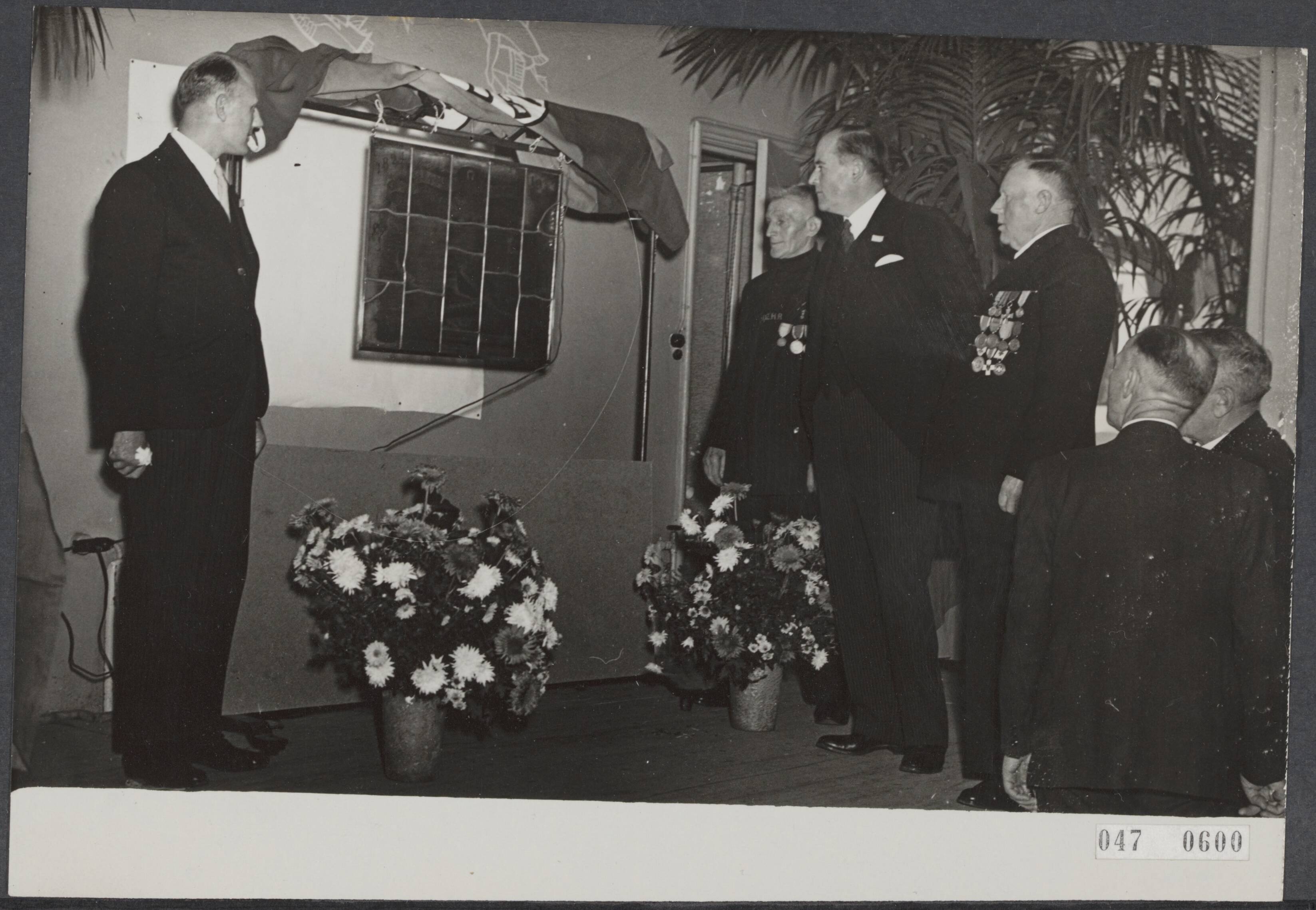 Fotocollectie Elsevier Binnenland — De gezamenlijke bemanning van de Noord-Zuid-Hollandse Redding Maatschappij [NZRHM] heeft aan de directie van deze maatschappij t.g.v. het 125-jarig jubileum een glas in lood raam ten geschenke gegeven. Links van het raam de heer W. Klijn, inspecteur, aan de andere kant vlnr. schipper Douwe Tot, H. Th. de Booy, directeur der NZHRM en schipper Mees Toxopeus. — Foto: ANP / RVD of rechtenvrij. Licentie: Set B: Rechtenvrij / Publiek Domein. Bron: Nationaal Archief. http://hdl.handle.net/10648/adffde2a-d0b4-102d-bcf8-003048976d84