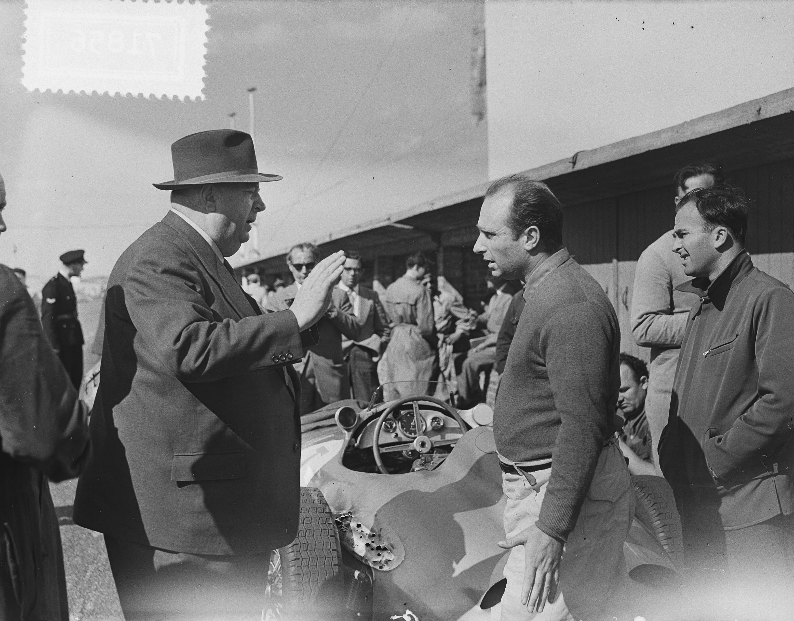 Fotocollectie Anefo — Training voor de Grote Prijs van Nederland op Zandvoort. Leider van de Mercedesploeg Alfred Neubauer (met hoed) in gesprek met de Argentijnse coureur Juan-Manuel Fangio — Foto: Bilsen, Joop van / Anefo. Licentie: Set B: Rechtenvrij / Publiek Domein. Bron: Nationaal Archief. http://hdl.handle.net/10648/a936bc74-d0b4-102d-bcf8-003048976d84