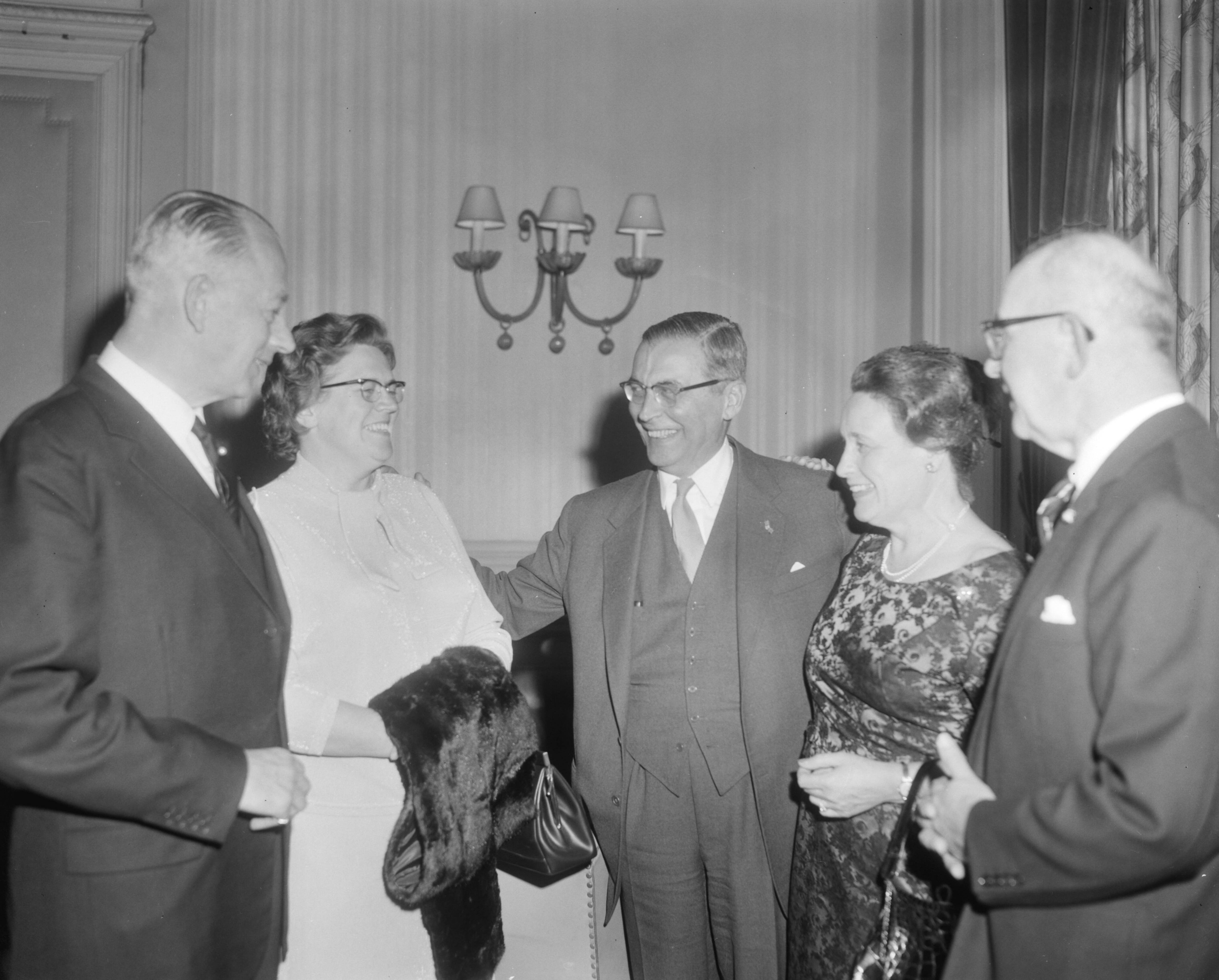Viering van het tienjarig jubileum van het Nederlands Genootschap van Burgemeesters in het Kurhaus te Scheveningen — Burgemeester van Amsterdam Van Hall (midden) en Burgemeester Kolfschoten van Den Haag (rechts) in gezelschap van twee burgemeestersvrouwen — Foto: Bilsen, Joop van / Anefo. Licentie: Set B: Rechtenvrij / Publiek Domein. Bron: Nationaal Archief. http://hdl.handle.net/10648/aac6688c-d0b4-102d-bcf8-003048976d84