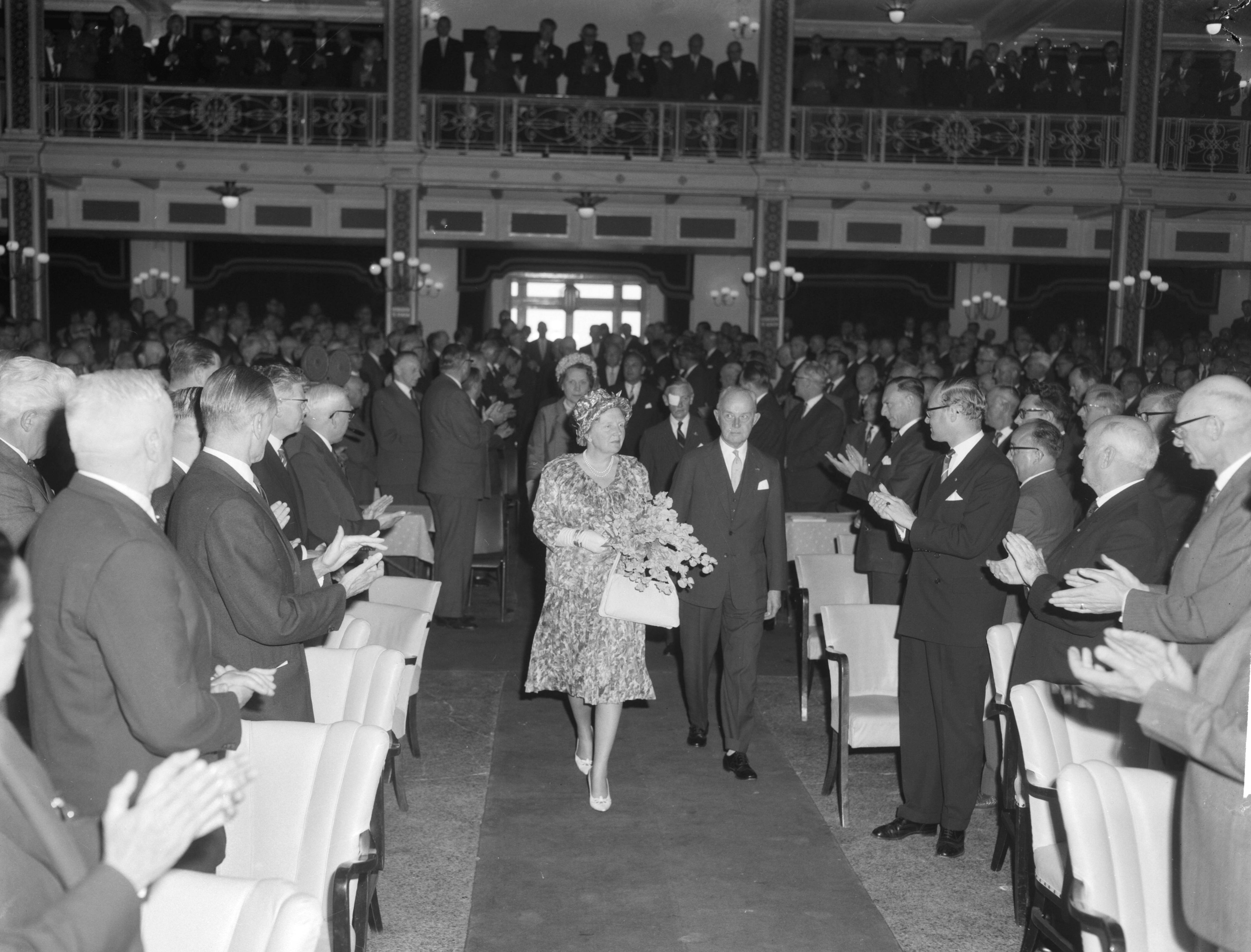 Fotocollectie Anefo — Koningin Juliana is aanwezig bij de viering van het 50-jarig bestaan van de Vereniging van Nederlandse Gemeenten in de Kurzaal te Scheveningen. Binnnenkomst van de koningin, geflankeerd door burgemeester Kolfschoten — Foto: Bilsen, Joop van / Anefo. Licentie: Set B: Rechtenvrij / Publiek Domein. Bron: Nationaal Archief. http://hdl.handle.net/10648/aa0b7cb6-d0b4-102d-bcf8-003048976d84