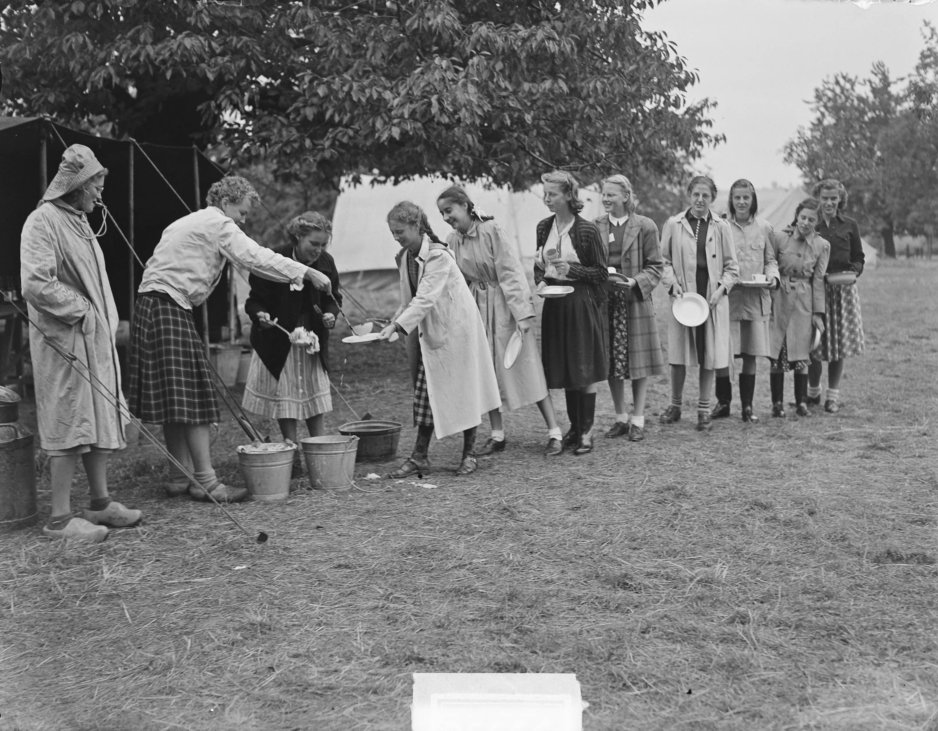 Fotocollectie Anefo — Kamp Mheer. Meisjes halen eten — Foto: Oorschot, […] van / Anefo. Licentie: Set B: Rechtenvrij / Publiek Domein. Bron: Nationaal Archief. http://hdl.handle.net/10648/a8cc41fa-d0b4-102d-bcf8-003048976d84