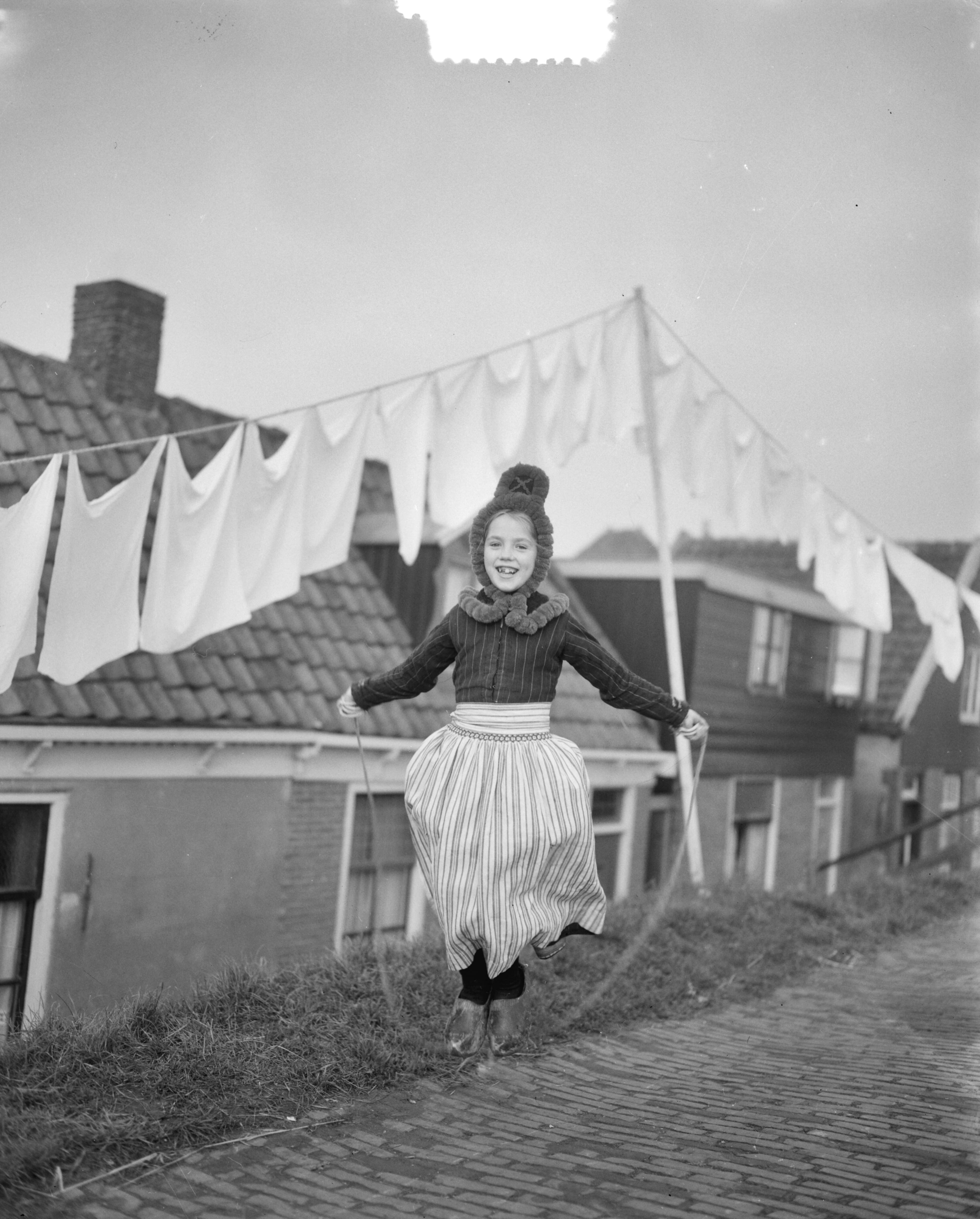 Opnamen in Volendam (familie) kinderspel — Opnamen in Volendam. Meisje in klederdracht springt touwtje — Foto: Duinen, G.W. van / Anefo. Licentie: Set B: Rechtenvrij / Publiek Domein. Bron: Nationaal Archief. http://hdl.handle.net/10648/a919b048-d0b4-102d-bcf8-003048976d84