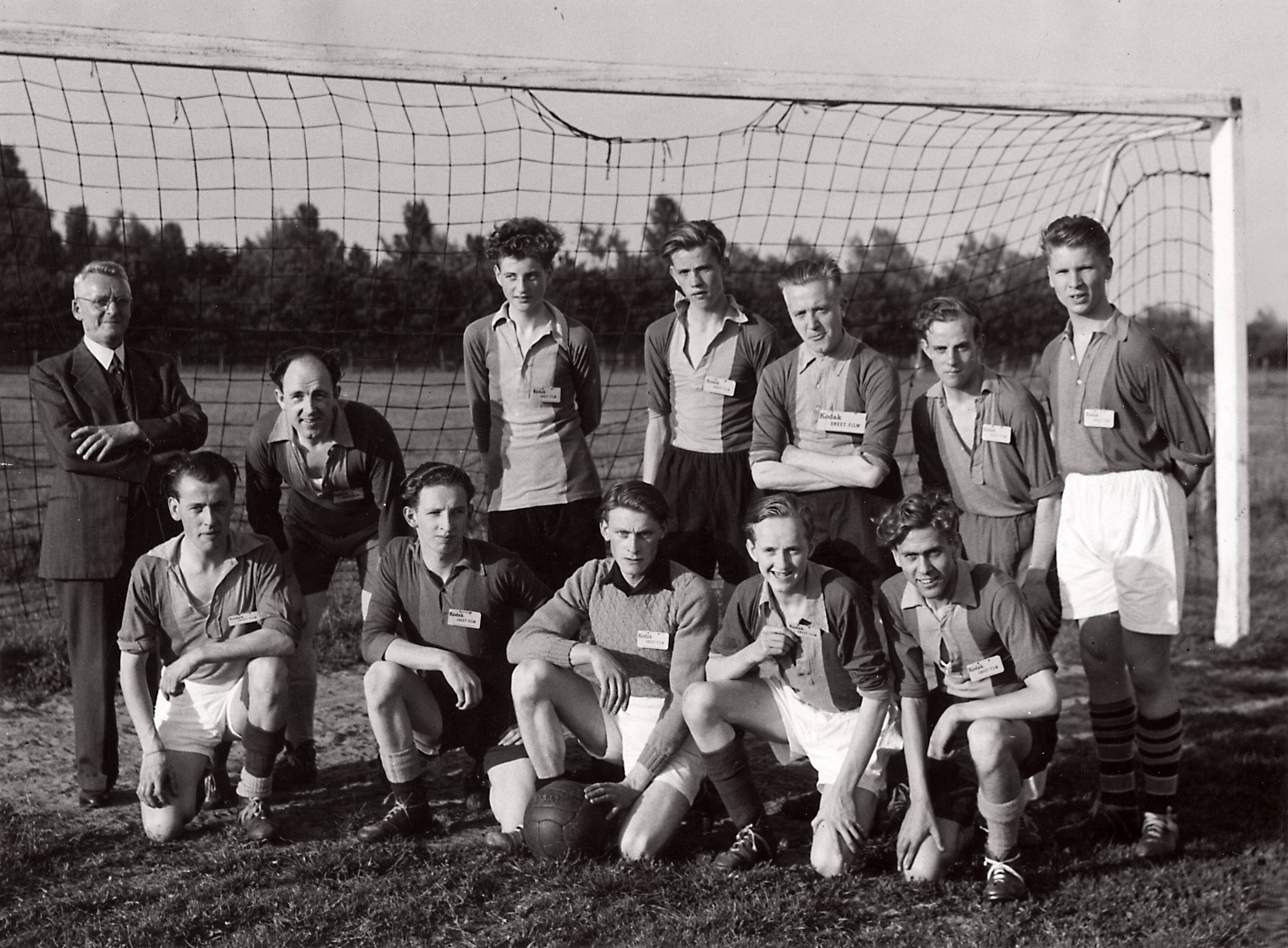 Sportactiviteiten personeel Drukkerij N.V. De Spaarnestad / Voetbal, o.a. F.C. Panorama — [Serie bedrijfsvoetbal Spaarnestad] elftal "Fotografie" [ voetbalelftal poseert in doel] [op hun borst is een kaartje met het opschrift "Kodak Street Film" vastgepind] — Foto: Fotograaf Onbekend / Fotobureau onbekend / Spaarnestad Photo (05887). Licentie: Set B: Rechtenvrij / Publiek Domein. Bron: Nationaal Archief. http://hdl.handle.net/10648/35429da6-3f22-a382-e063-6df0900a6686