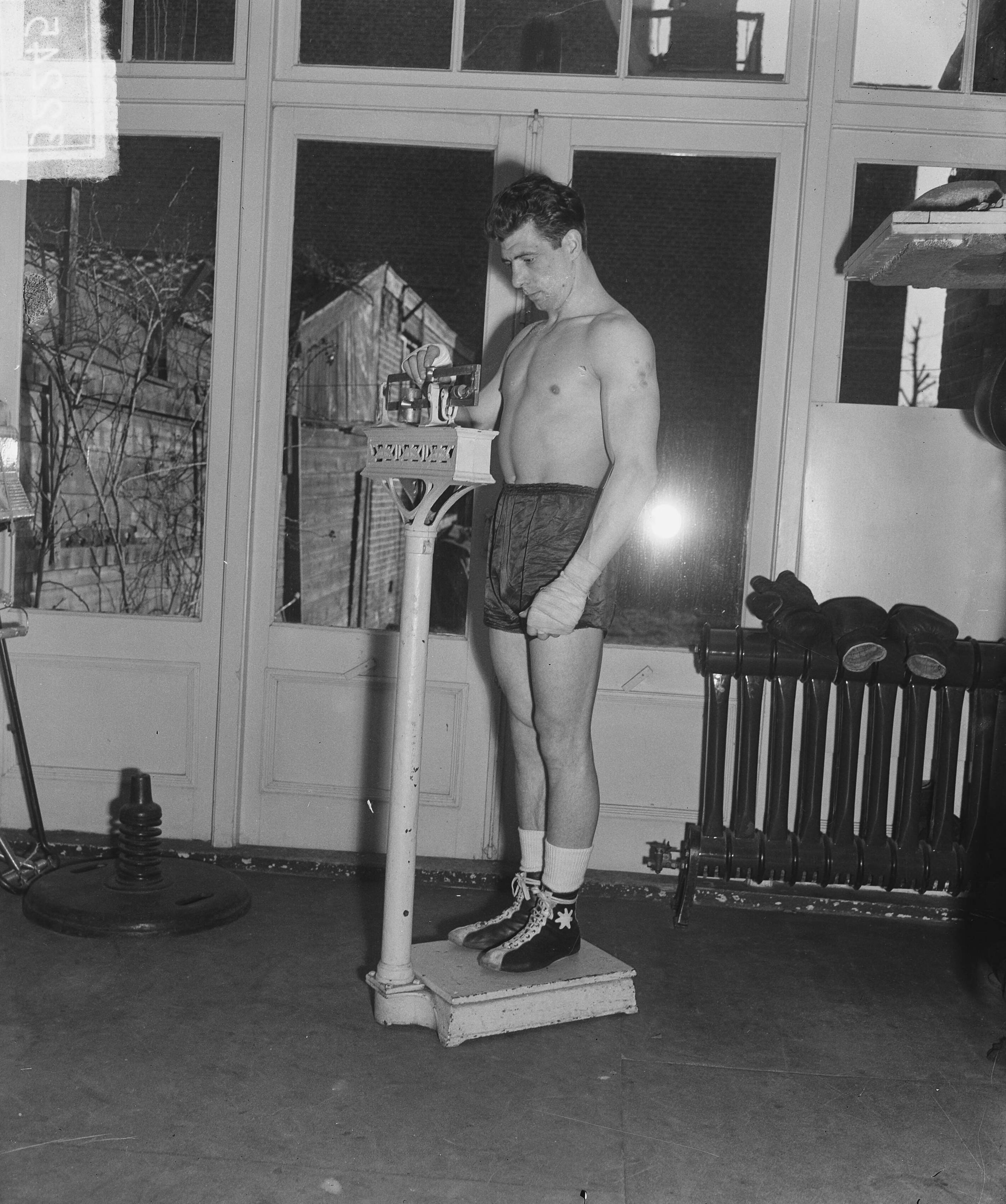 Fotocollectie Anefo — Training bokser Luc Van Dam in Den Haag. Op de weegschaal — Foto: Merk, Ben / Anefo. Licentie: Set B: Rechtenvrij / Publiek Domein. Bron: Nationaal Archief. http://hdl.handle.net/10648/a8c37f5c-d0b4-102d-bcf8-003048976d84