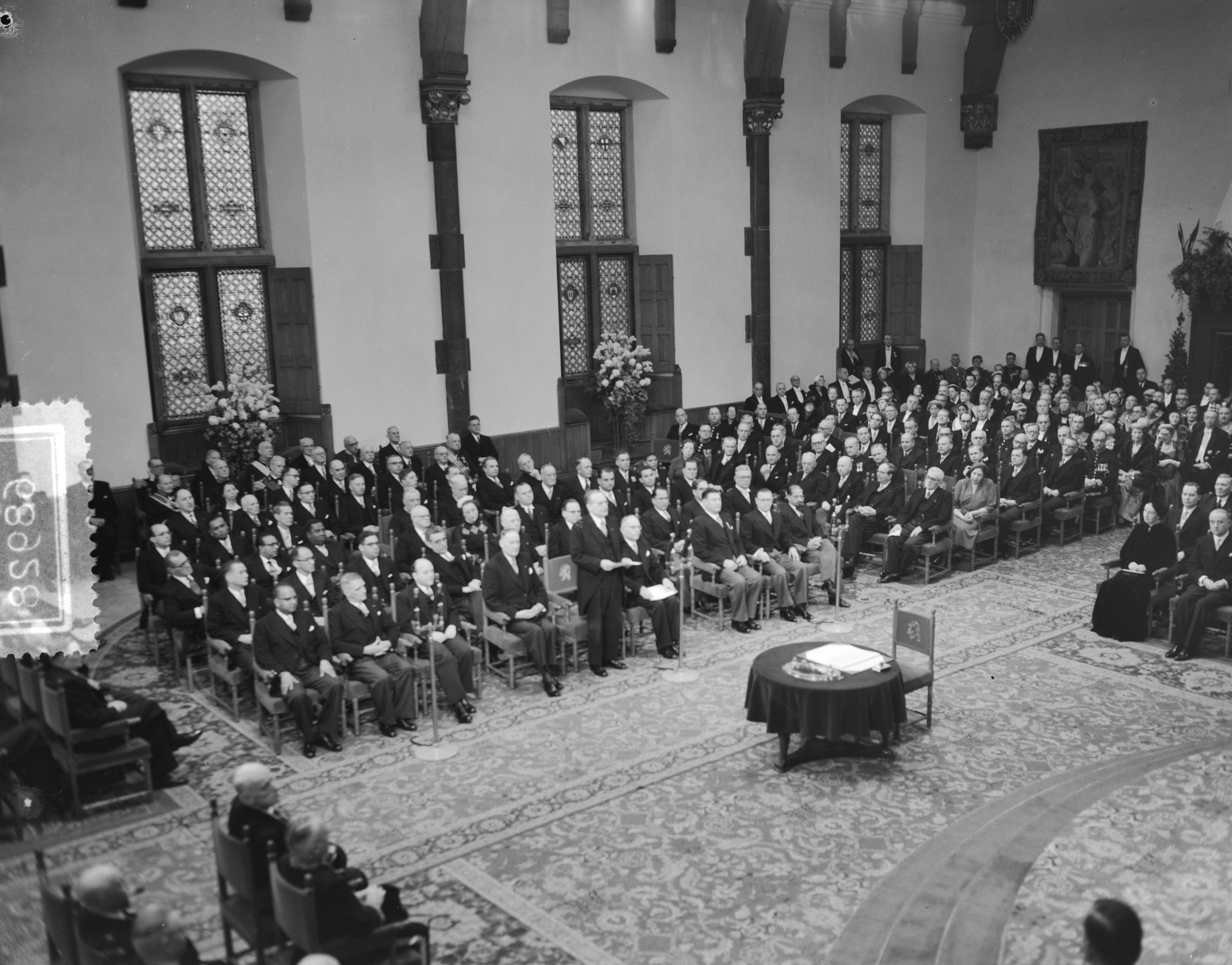 Koningin Juliana ondertekent in een plechtige bijeenkomst in de Ridderzaal in Den Haag de Acte van Bevestiging van het Statuut voor het Koninkrijk — Ondertekening van de Acte van Bevestiging van het Statuut van het Koninkrijk in de Ridderzaal te Den Haag. Een van de ministers houdt een toespraak — Foto: Noske, J.D. / Anefo. Licentie: Set B: Rechtenvrij / Publiek Domein. Bron: Nationaal Archief. http://hdl.handle.net/10648/a92e2280-d0b4-102d-bcf8-003048976d84