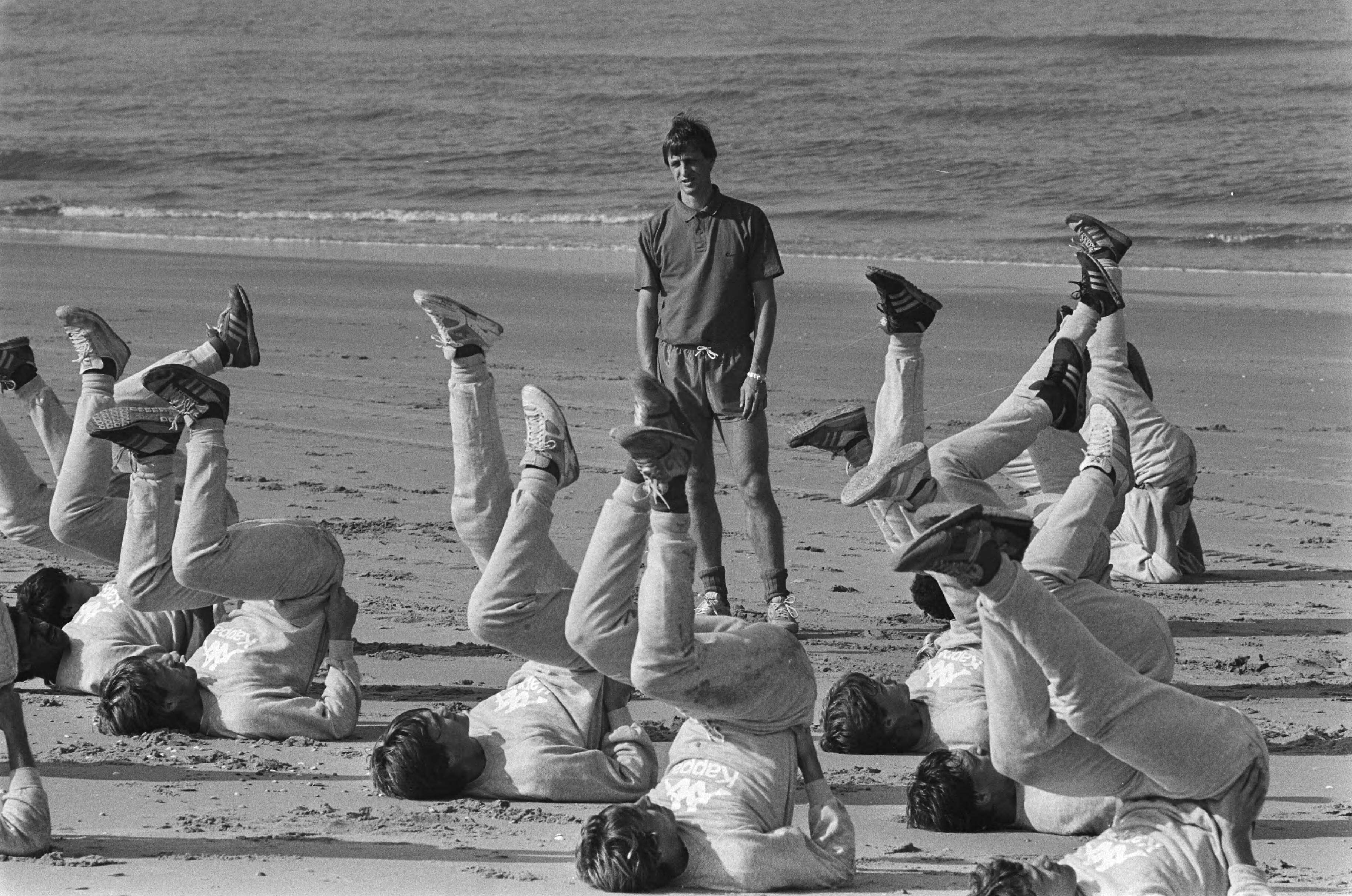 Fotocollectie Anefo — Training Ajax op strand Wassenaar; technisch directeur Johan Cruijff kijkt naar trainende spelers — Foto: Croes, Rob C. / Anefo. Licentie: Set B: Rechtenvrij / Publiek Domein. Bron: Nationaal Archief. http://hdl.handle.net/10648/ad4b0edc-d0b4-102d-bcf8-003048976d84