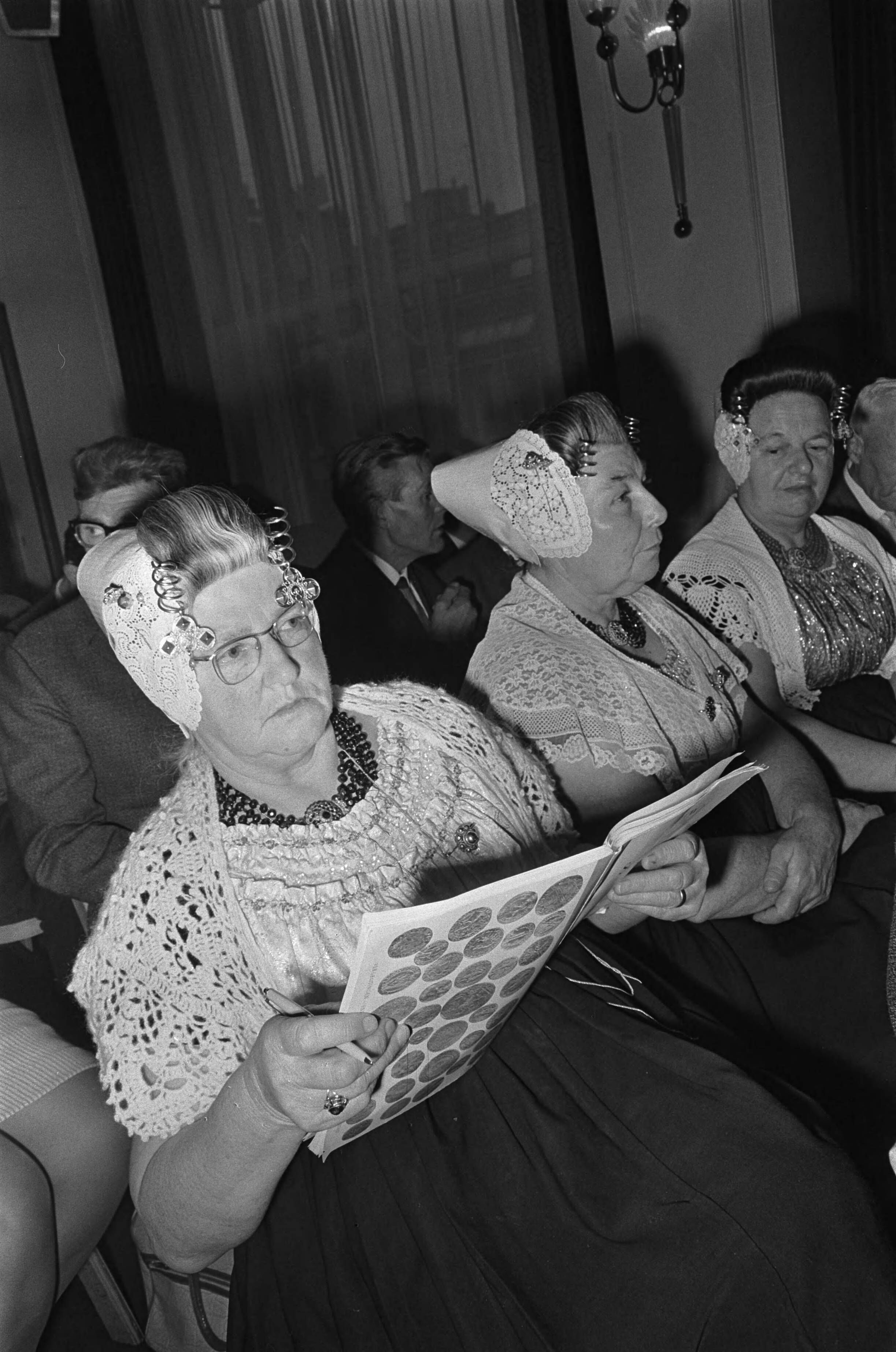Serooskerker munten geveild — Traditioneel geklede Zeeuwse vrouwen bekijken de catalogus — Foto: Fotograaf Onbekend / Anefo. Licentie: Set B: Rechtenvrij / Publiek Domein. Bron: Nationaal Archief. http://hdl.handle.net/10648/ab053d8c-d0b4-102d-bcf8-003048976d84