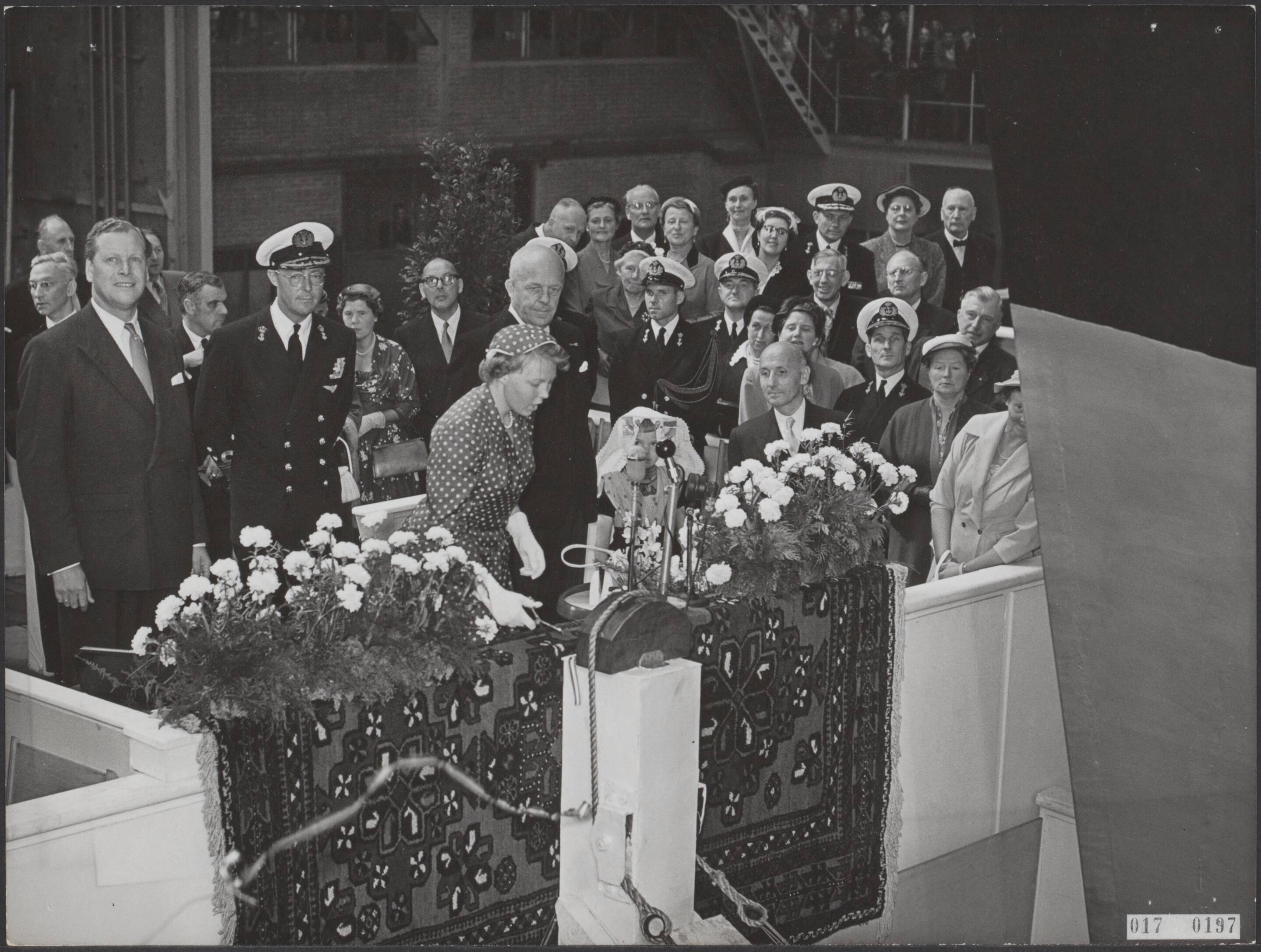 Fotocollectie Elsevier Binnenland — Prinses Beatrix heeft te Vlissingen bij scheepswerf De Schelde de onderzeebootjager Hr. Ms. "Limburg" te water gelaten. Prinses Beatrix knipt het lint door. Op het podium vlnr. J.W. Hupkes, de directeur van de werf; prins Bernhard; prinses Beatrix en achter haar ir. C. Staf, minister van Oorlog en Marine — Foto: Fotograaf Onbekend / Anefo. Licentie: Set B: Rechtenvrij / Publiek Domein. Bron: Nationaal Archief. http://hdl.handle.net/10648/adbd0cb2-d0b4-102d-bcf8-003048976d84