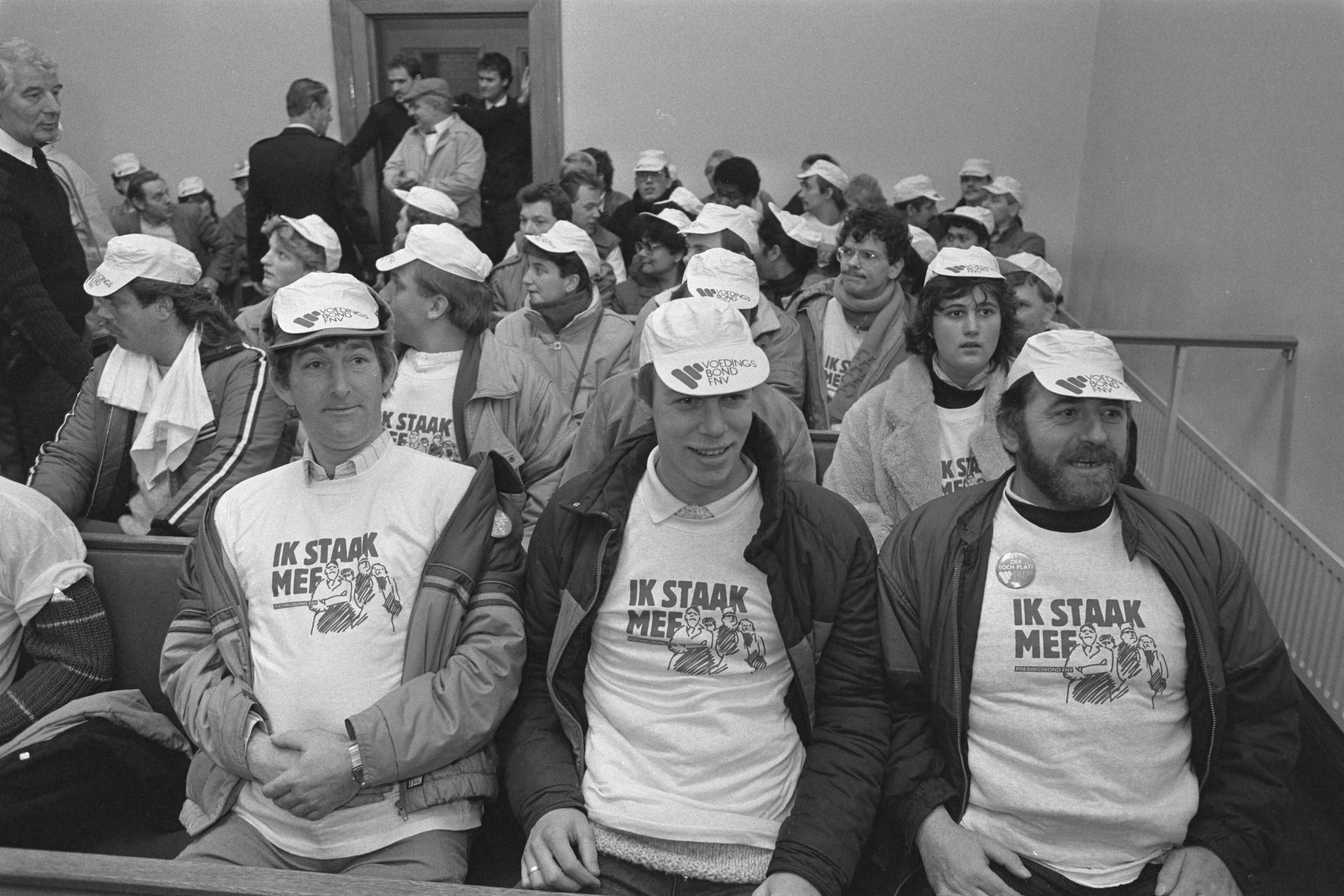 Fotocollectie Anefo — Kort geding Ahold tegen Voedingsbond FNV i.v.m. staking bij Centr. Slagerij (Utrecht); stakers met pet en t-shirt in de rechtszaal — Foto: Croes, Rob C. / Anefo. Licentie: Set B: Rechtenvrij / Publiek Domein. Bron: Nationaal Archief. http://hdl.handle.net/10648/ad5a25b6-d0b4-102d-bcf8-003048976d84