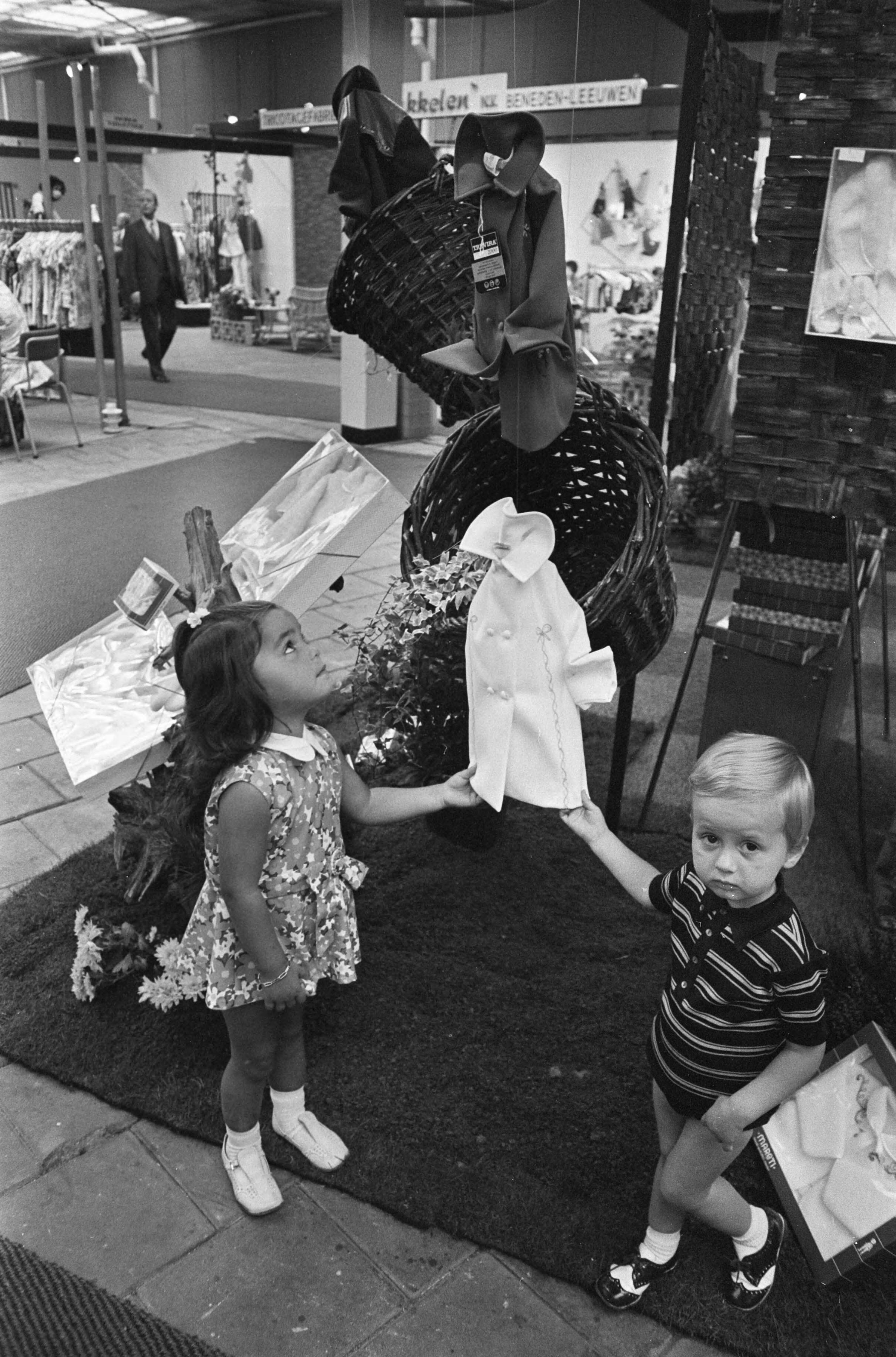 Fotocollectie Anefo — Vakbeurs "Het Kind" in Utrecht; twee kinderen bekijken kledingstukken — Foto: Mieremet, Rob / Anefo. Licentie: Set B: Rechtenvrij / Publiek Domein. Bron: Nationaal Archief. http://hdl.handle.net/10648/aba43482-d0b4-102d-bcf8-003048976d84