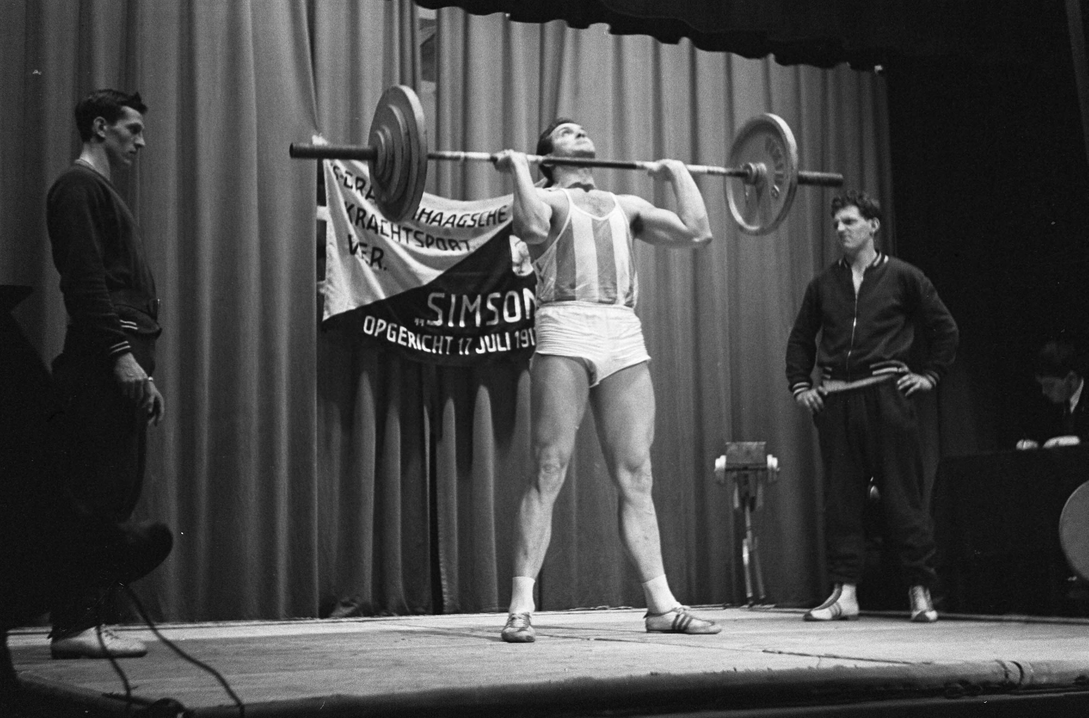 Fotocollectie Anefo — Eef Kamerbeek als gewichtheffer. Eef in aktie op he tNederlands kampioenschap gewichtheffen 2e klasse in Amicitia te Den Haag — Foto: Koch, Eric / Anefo. Licentie: Set B: Rechtenvrij / Publiek Domein. Bron: Nationaal Archief. http://hdl.handle.net/10648/aa293602-d0b4-102d-bcf8-003048976d84