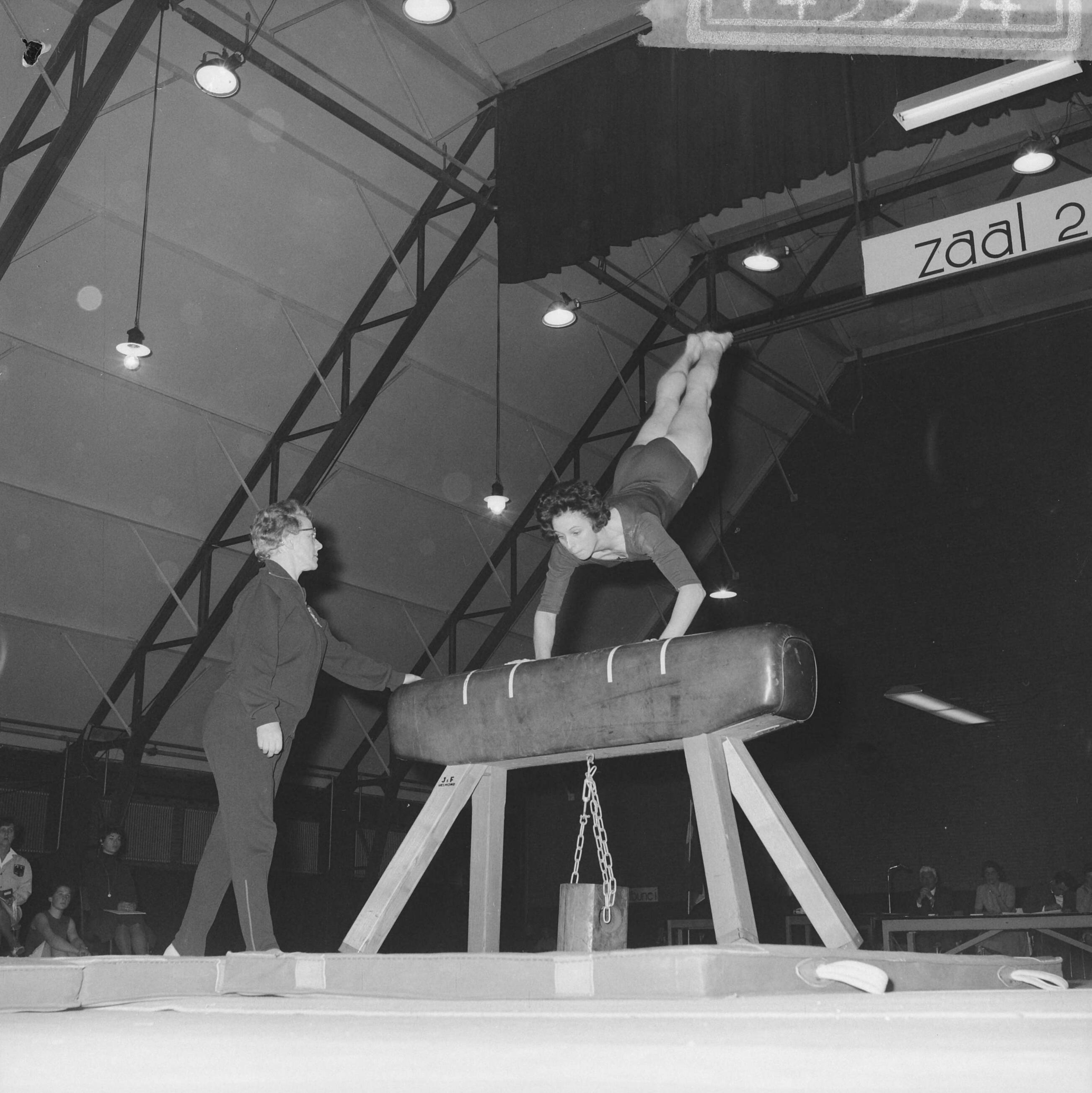 Fotocollectie Anefo — Turninterland Nederland-West-Duitsland in de Centrale Veilinghal te Aalsmeer. Nederlandse turnster bij paardsprong — Foto: Nijs, Jac. de / Anefo. Licentie: Set B: Rechtenvrij / Publiek Domein. Bron: Nationaal Archief. http://hdl.handle.net/10648/aa200708-d0b4-102d-bcf8-003048976d84
