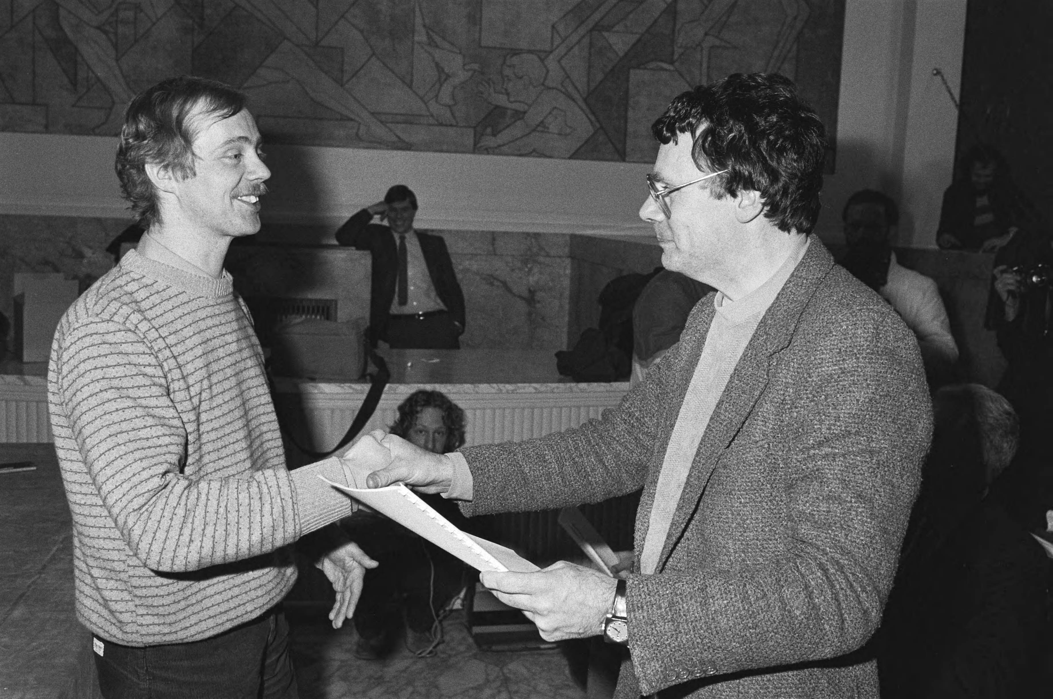 Fotocollectie Anefo — Nederlandse kunstenaars presenteren in Den Haag rapport bezuinigingen en gevolgen daarvan. Aanbieden van het rapport — Foto: Antonisse, Marcel / Anefo. Licentie: Set B: Rechtenvrij / Publiek Domein. Bron: Nationaal Archief. http://hdl.handle.net/10648/ad0d21e4-d0b4-102d-bcf8-003048976d84