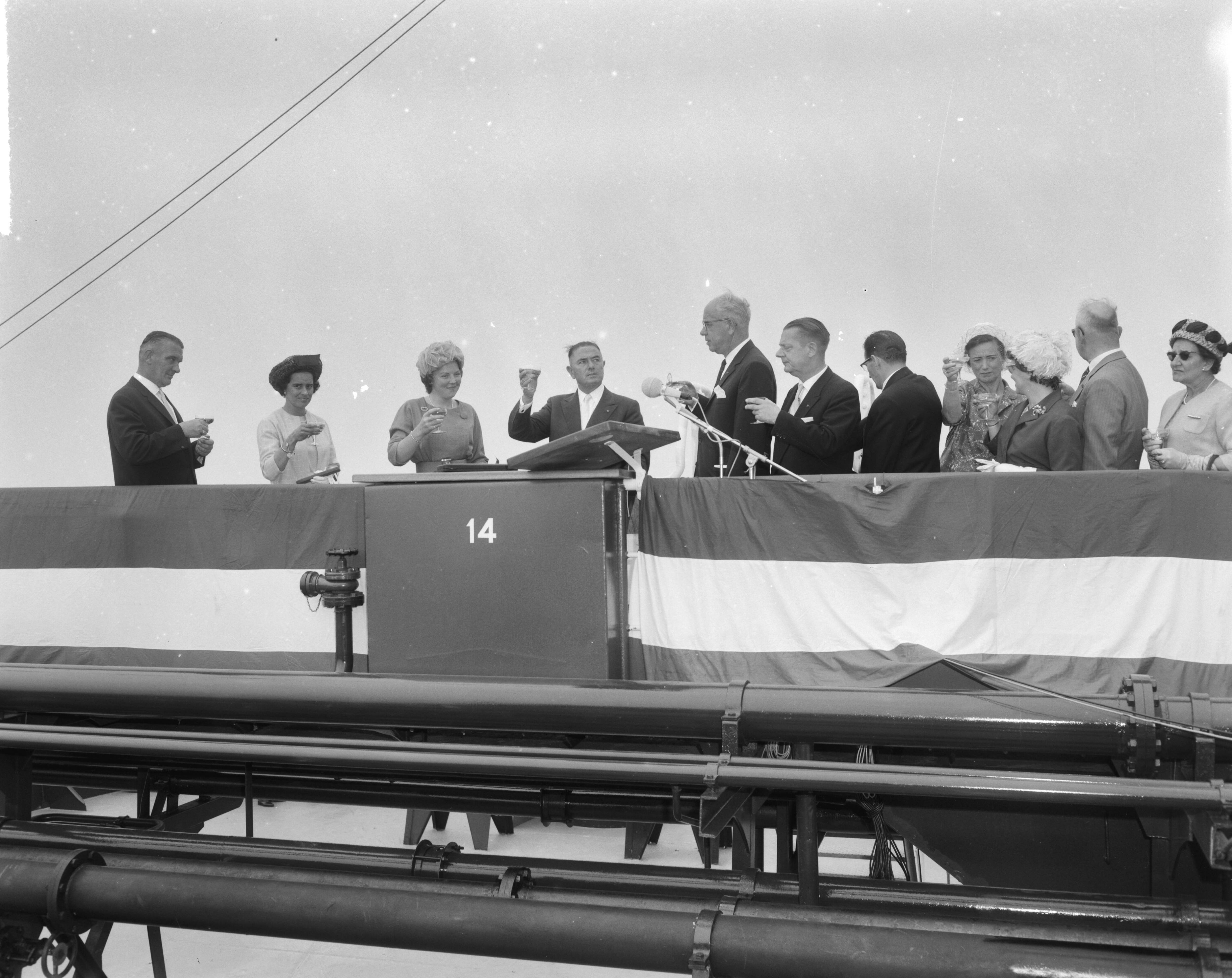 Fotocollectie Anefo — Prinses Beatrix doopte de grootste tanker "Esso Den Haag" op de Noordzee. De aanwezigen heffen het glas. Links van prinses Beatrix haar particuliere secretaresse mej. M.C.C. Wijnen en rechts Cornelis Verolme en de president-directeur van Esso Nederland, C.R. Smit — Foto: Bilsen, Joop van / Anefo. Licentie: Set B: Rechtenvrij / Publiek Domein. Bron: Nationaal Archief. http://hdl.handle.net/10648/aa3dcb58-d0b4-102d-bcf8-003048976d84