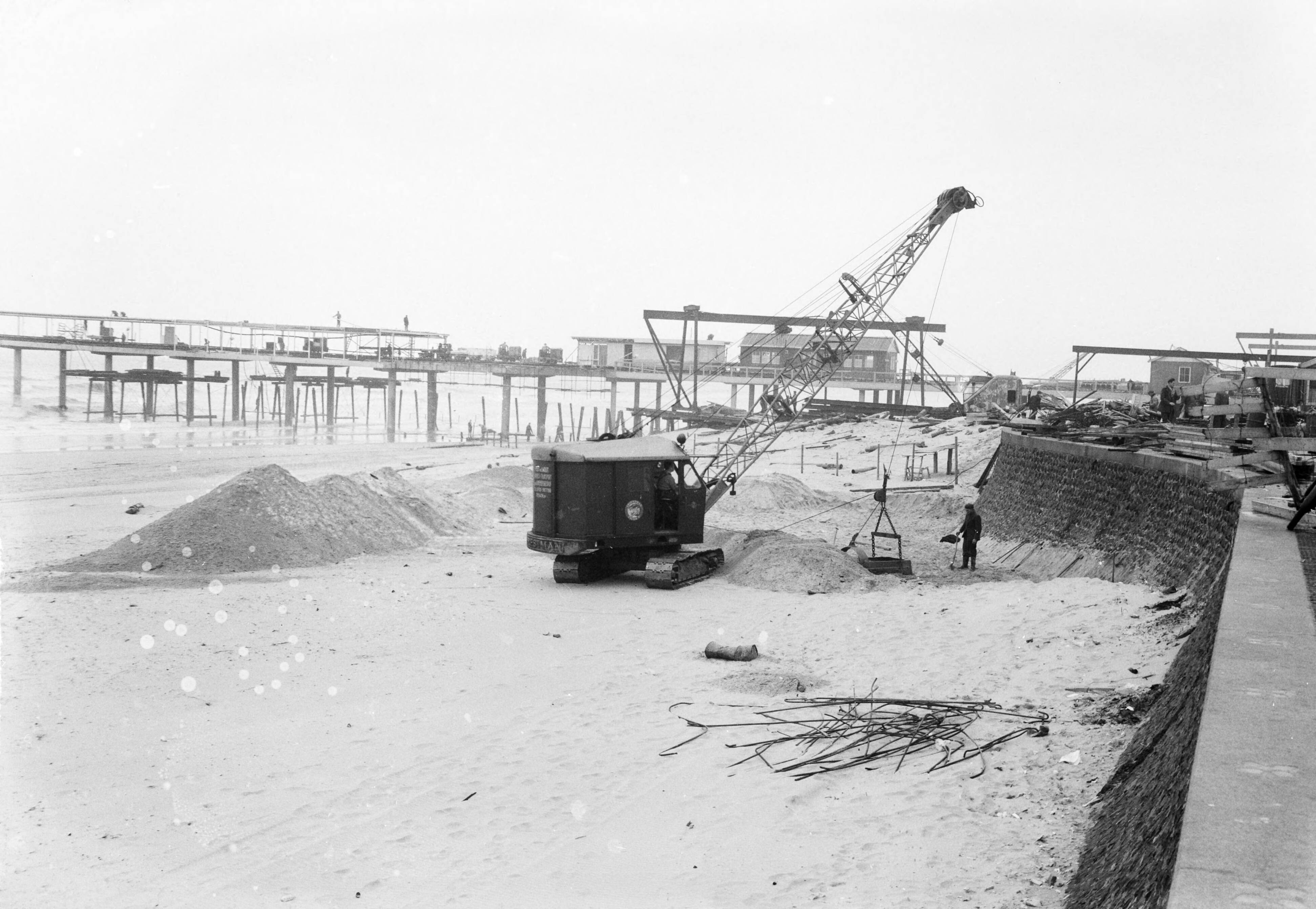 Fotocollectie Anefo — Egaliseren van het strand te Scheveningen voor het komend badseizoen — Foto: Behrens, Herbert F. / Anefo. Licentie: Set B: Rechtenvrij / Publiek Domein. Bron: Nationaal Archief. http://hdl.handle.net/10648/a9ccee38-d0b4-102d-bcf8-003048976d84