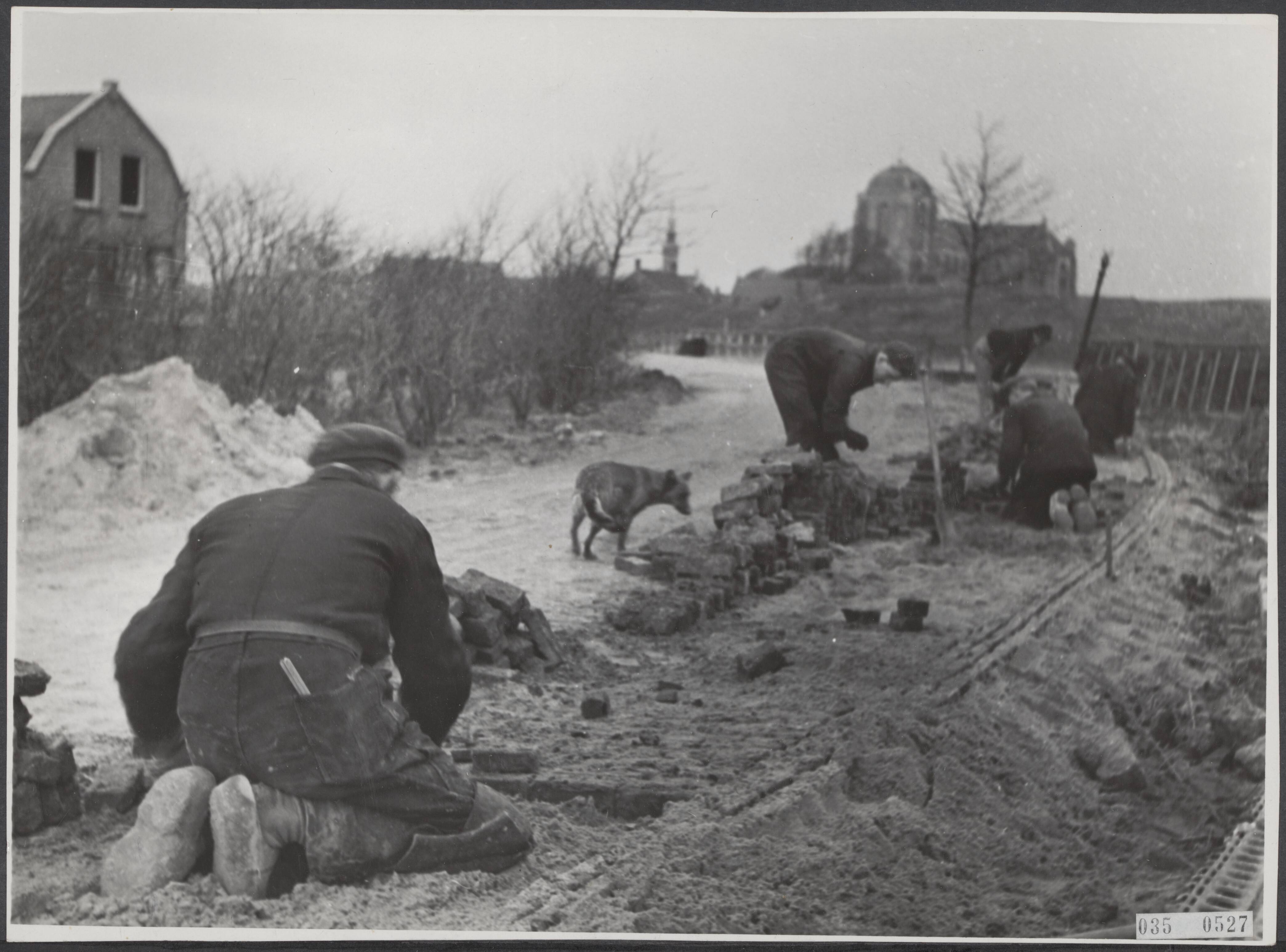 Fotocollectie Elsevier Binnenland — Walcheren. Naar schatting zijn in het Walcherse land omstreeks 10 kilometer wegen geheel weggeslagen, andere gedeeltelijk vernield. De wederopbouw moet door het herstel van wegen ingeleid worden. Hier wordt de weg naar Veere hersteld — Foto: Breijer, Charles / Anefo. Licentie: Set B: Rechtenvrij / Publiek Domein. Bron: Nationaal Archief. http://hdl.handle.net/10648/adeaedb2-d0b4-102d-bcf8-003048976d84