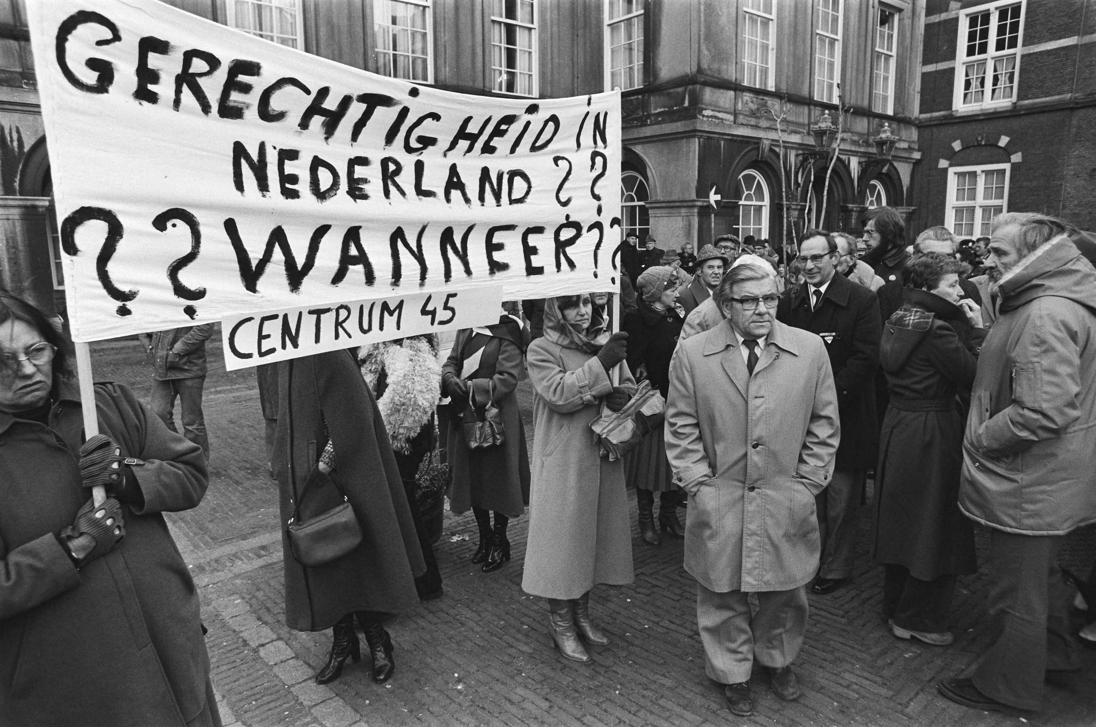 Fotocollectie Anefo — Demonstratie tegen vrijlating Menten op Binnenhof ( Den Haag ); demonstrant met fotos van kampen — Foto: Croes, Rob C. / Anefo. Licentie: Set B: Rechtenvrij / Publiek Domein. Bron: Nationaal Archief. http://hdl.handle.net/10648/acc0db72-d0b4-102d-bcf8-003048976d84