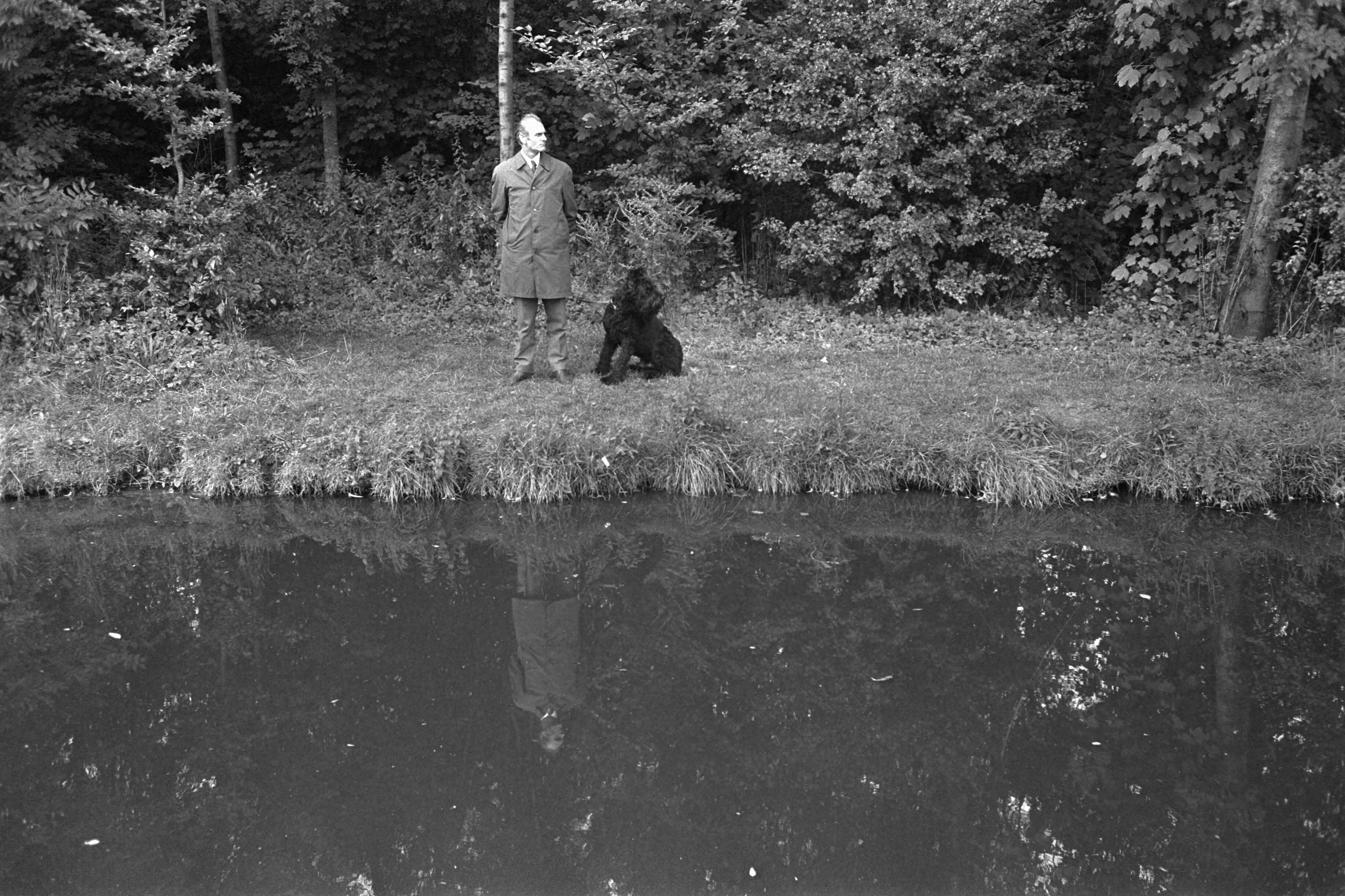 Fotocollectie Anefo — Paleis Huis ten Bosch , Den Haag , wordt bewaakt i.v.m. aanstaand bezoek president Soeharto; politieman in burger met hond in bos — Foto: Koch, Eric / Anefo. Licentie: Set B: Rechtenvrij / Publiek Domein. Bron: Nationaal Archief. http://hdl.handle.net/10648/aba1ba54-d0b4-102d-bcf8-003048976d84