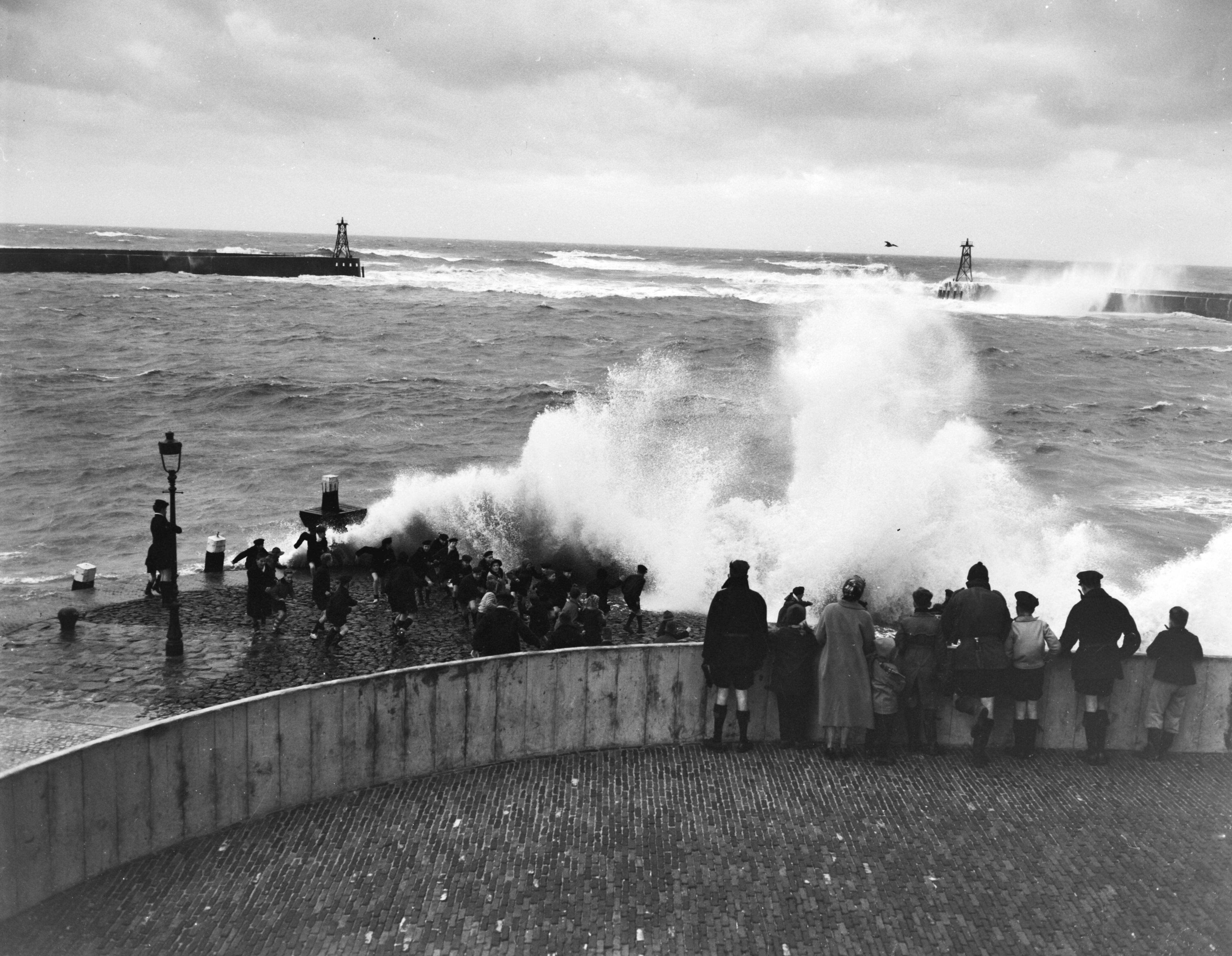 Fotocollectie Anefo — Westerstrom aan de kust van Scheveningen. Overslaande golven, kinderen rennen weg — Foto: Hartkamp, […] / Anefo. Licentie: Set B: Rechtenvrij / Publiek Domein. Bron: Nationaal Archief. http://hdl.handle.net/10648/ad77012c-d0b4-102d-bcf8-003048976d84
