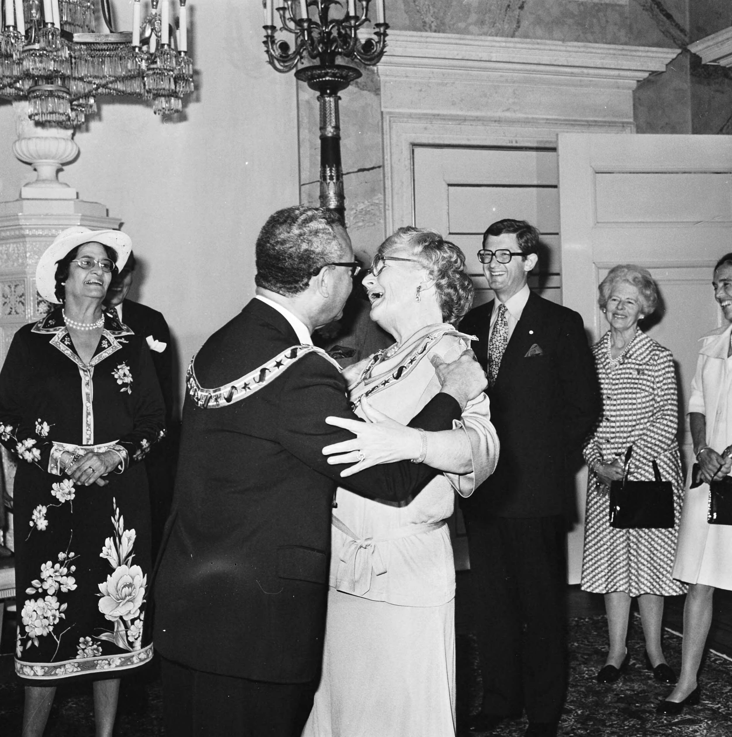 Fotocollectie Anefo — Koningin Juliana ontvangt de Surinaamse president Johan Ferrier op Soestdijk en krijgt hoge Surinaamse onderscheiding; Ferrier omhelst Hare Majesteit, links mevrouw Ferrier — Foto: Croes, Rob C. / Anefo. Licentie: Set B: Rechtenvrij / Publiek Domein. Bron: Nationaal Archief. http://hdl.handle.net/10648/ac9d15a2-d0b4-102d-bcf8-003048976d84