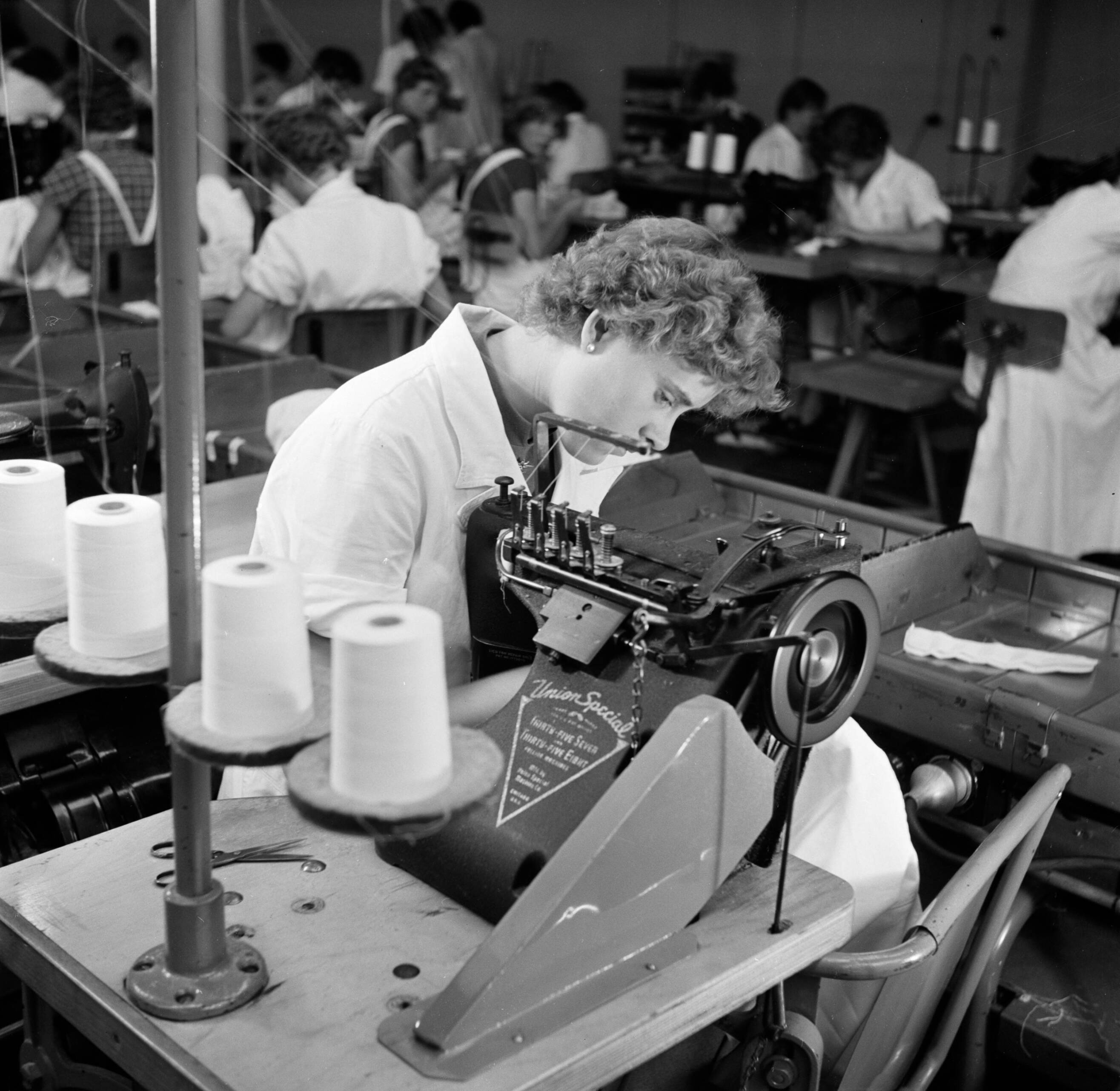 Reportage Kerko Haarlem — Naaimachine bij overhemdenbedrijf Kerko — Foto: Poll, Willem van de. Licentie: Set B: Rechtenvrij / Publiek Domein. Bron: Nationaal Archief. http://hdl.handle.net/10648/aecbc0d0-d0b4-102d-bcf8-003048976d84