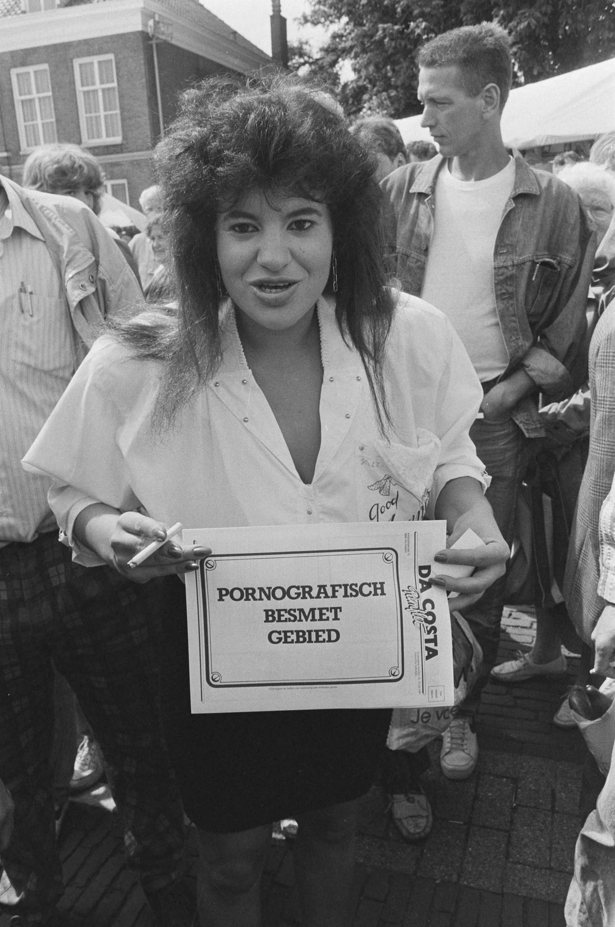 Fotocollectie Anefo — Kruistocht tegen porno van ex-EO-directeur L. P. Dorenbo in Veenendaal; Candy met sticker "pornograafisch besmet gebied" — Foto: Molendijk, Bart / Anefo. Licentie: Set B: Rechtenvrij / Publiek Domein. Bron: Nationaal Archief. http://hdl.handle.net/10648/ad627dec-d0b4-102d-bcf8-003048976d84