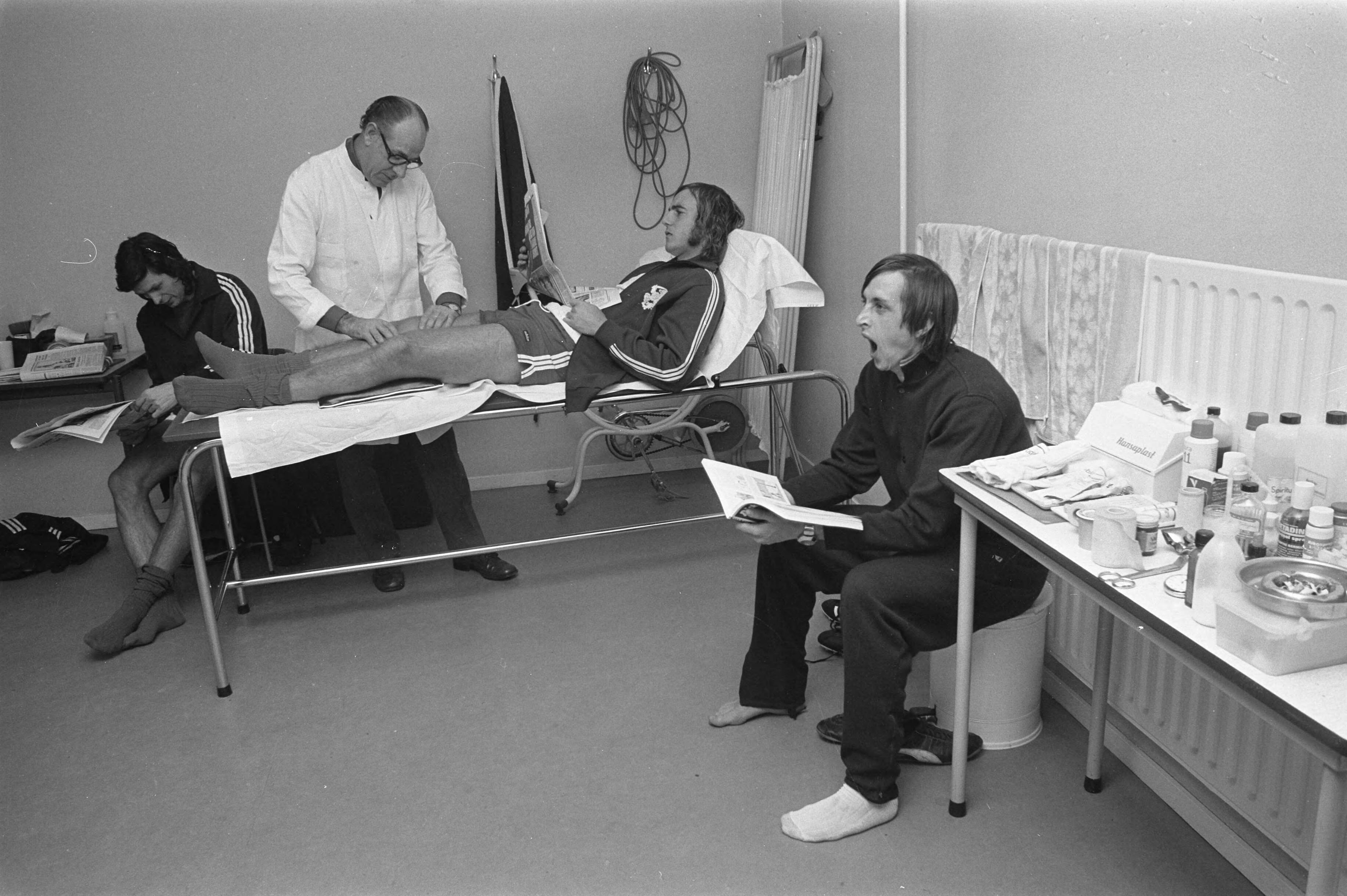 Fotocollectie Anefo — Selectie Nederlands Elftal in Zeist, in de massagekamer v.l.n.r. Suurbier, verzorger Pierre van den Akker , Neeskens (op massagetafel) en Cruijff — Foto: Verhoeff, Bert / Anefo. Licentie: Set B: Rechtenvrij / Publiek Domein. Bron: Nationaal Archief. http://hdl.handle.net/10648/abfdd00a-d0b4-102d-bcf8-003048976d84
