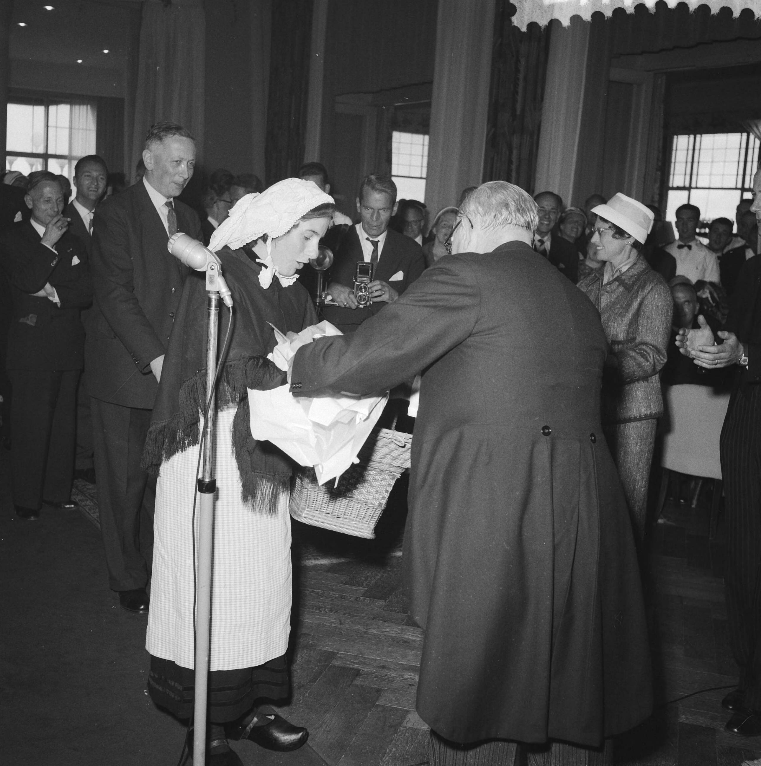 Fotocollectie Anefo — De directeur van het ANP, H.H.J. van de Pol, neemt afscheid in het Kurhaus te Scheveningen. "Zoete Lieve Gerritje" overhandigt geschenk aan Van de Pol — Foto: Behrens, Herbert F. / Anefo. Licentie: Set B: Rechtenvrij / Publiek Domein. Bron: Nationaal Archief. http://hdl.handle.net/10648/a9b310d0-d0b4-102d-bcf8-003048976d84