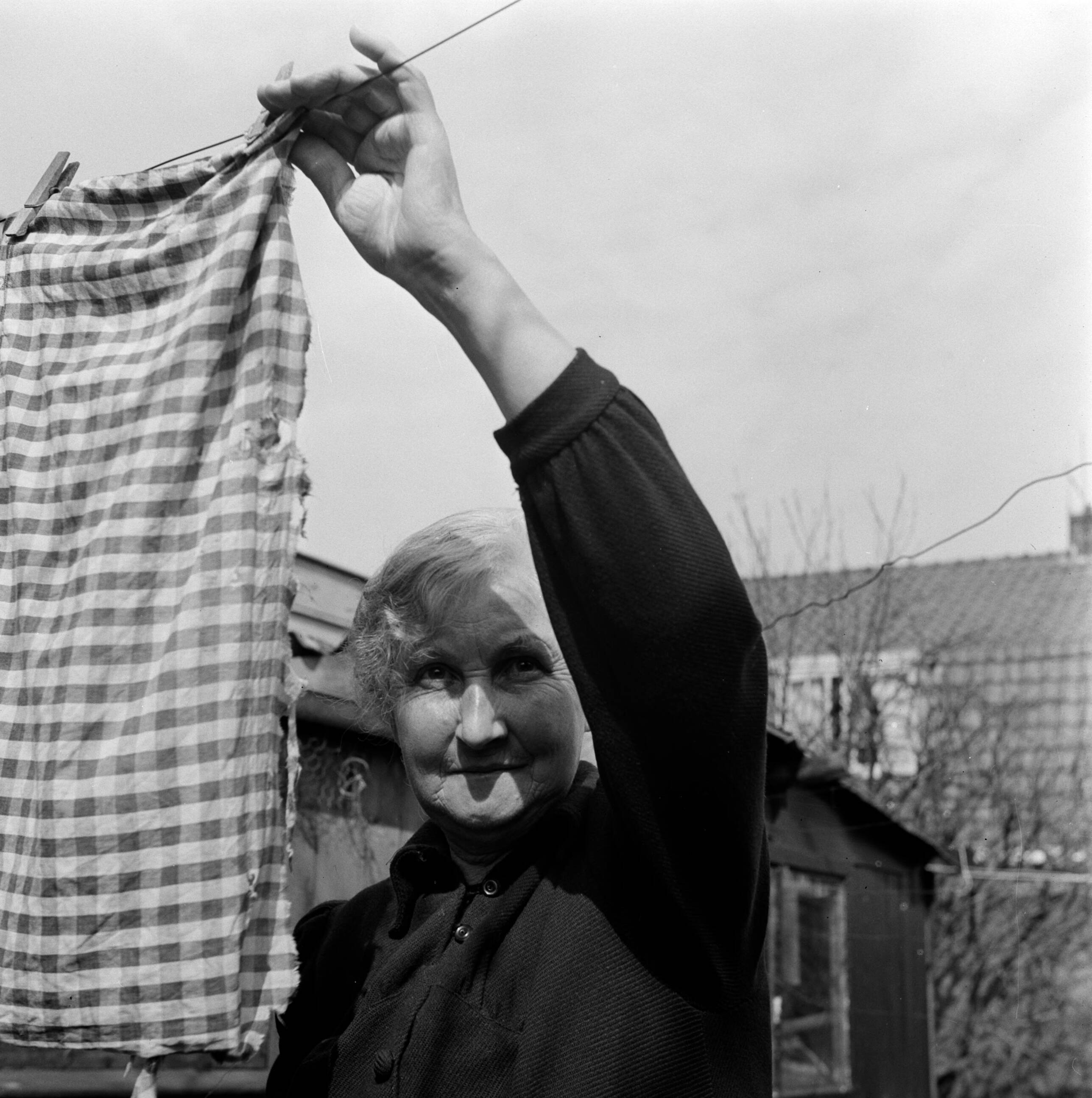 Fotocollectie Van de Poll — Moeder De Jong hangt de was op in de achtertuin van hun woning in Huizum (nu deel van Leeuwarden) — Foto: Poll, Willem van de. Licentie: Set B: Rechtenvrij / Publiek Domein. Bron: Nationaal Archief. http://hdl.handle.net/10648/aeccc8a4-d0b4-102d-bcf8-003048976d84